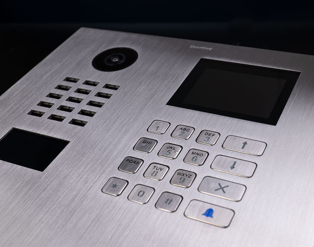 Stainless steel DoorBird door station close-up of camera, display, and keypad buttons