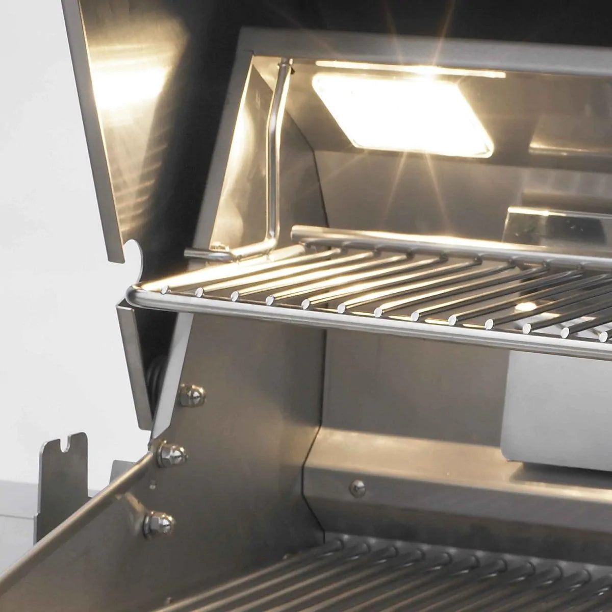 Built-in gas grill interior with cooking grates and bright overhead light
