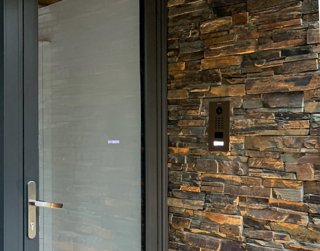 DoorBird D2101V IP video door station mounted on stone wall beside door