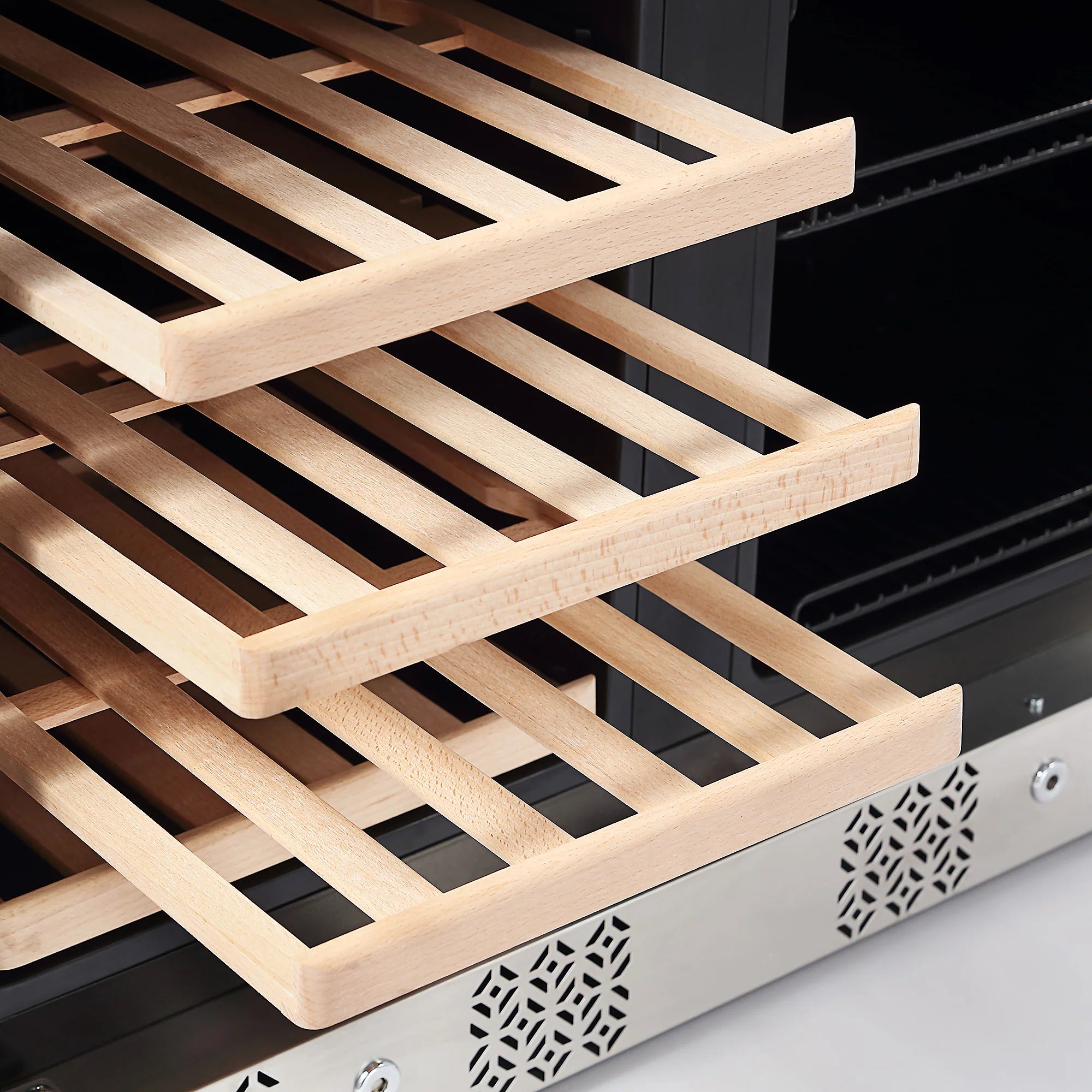 Wooden wine racks inside a stainless steel wine cooler with ventilated trim
