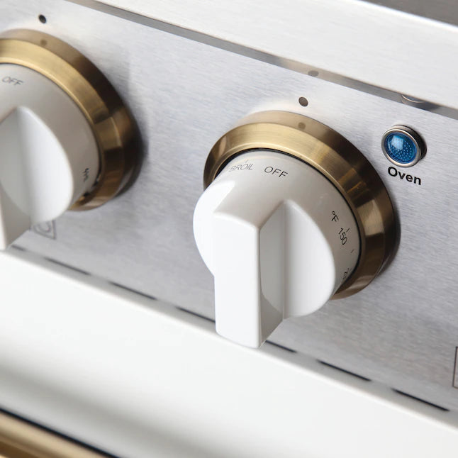 White oven control panel with gold-toned knobs, blue indicator light, and “Oven” dial