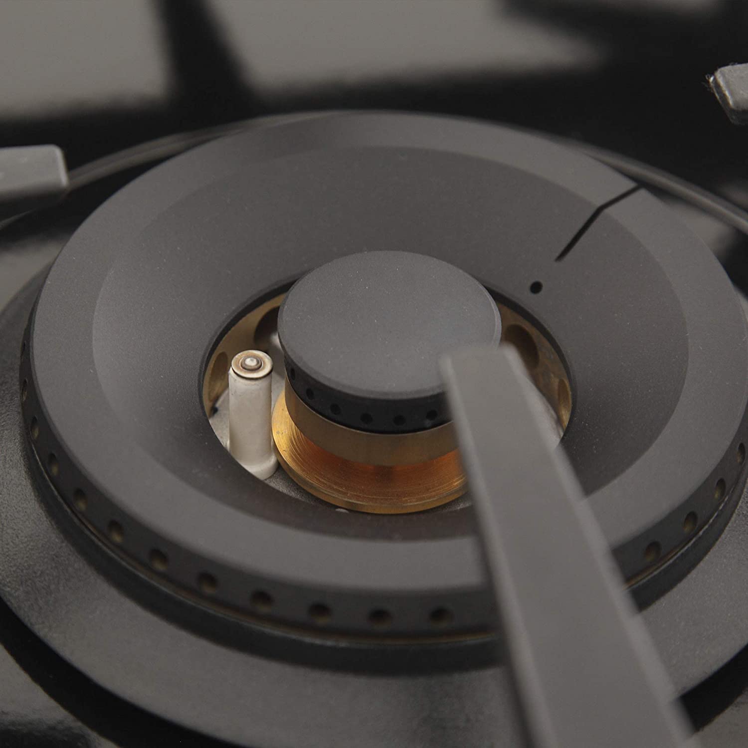 Gas burner head with black cap and brass ring on stainless cooktop
