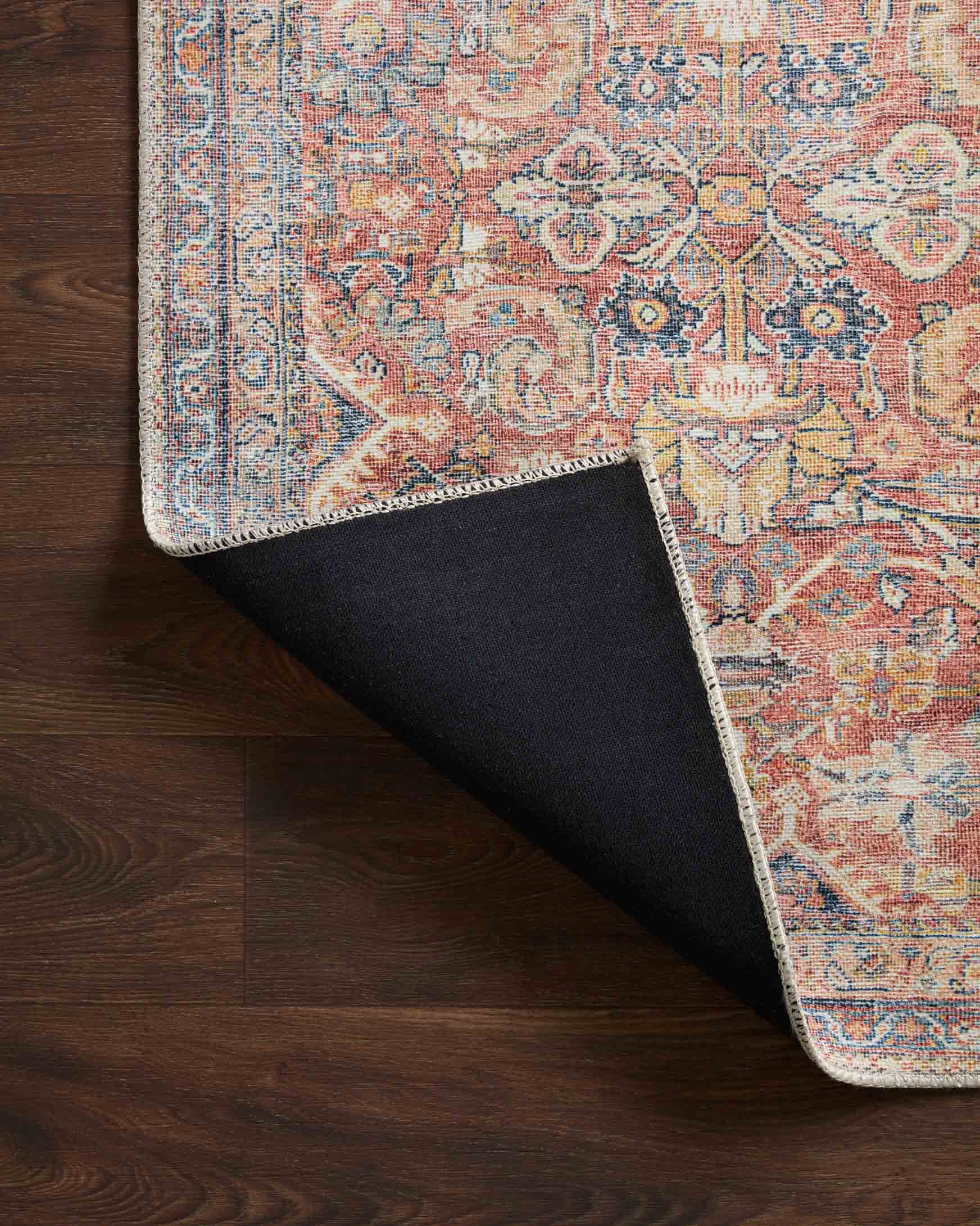 Traditional power-loomed rug corner with visible backing; rust and denim blue pattern.