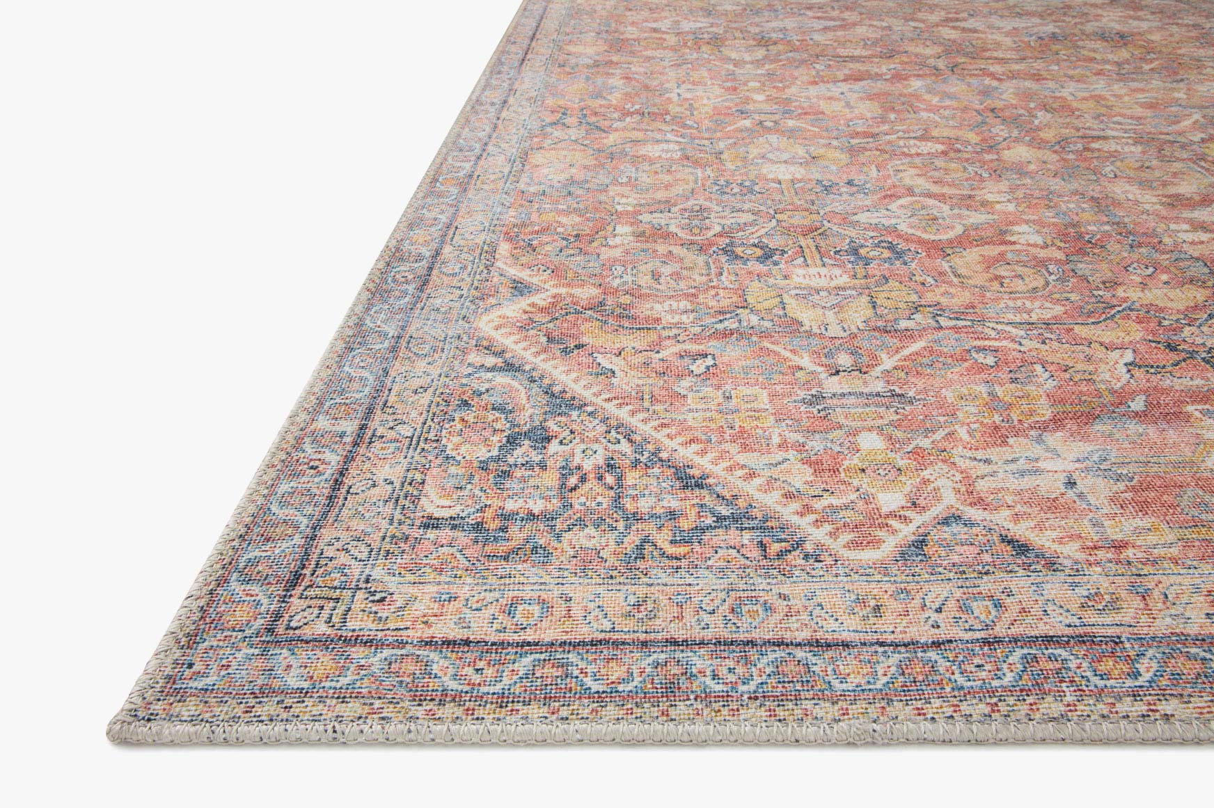 Traditional power-loomed rug corner with decorative border in rust and denim blue.