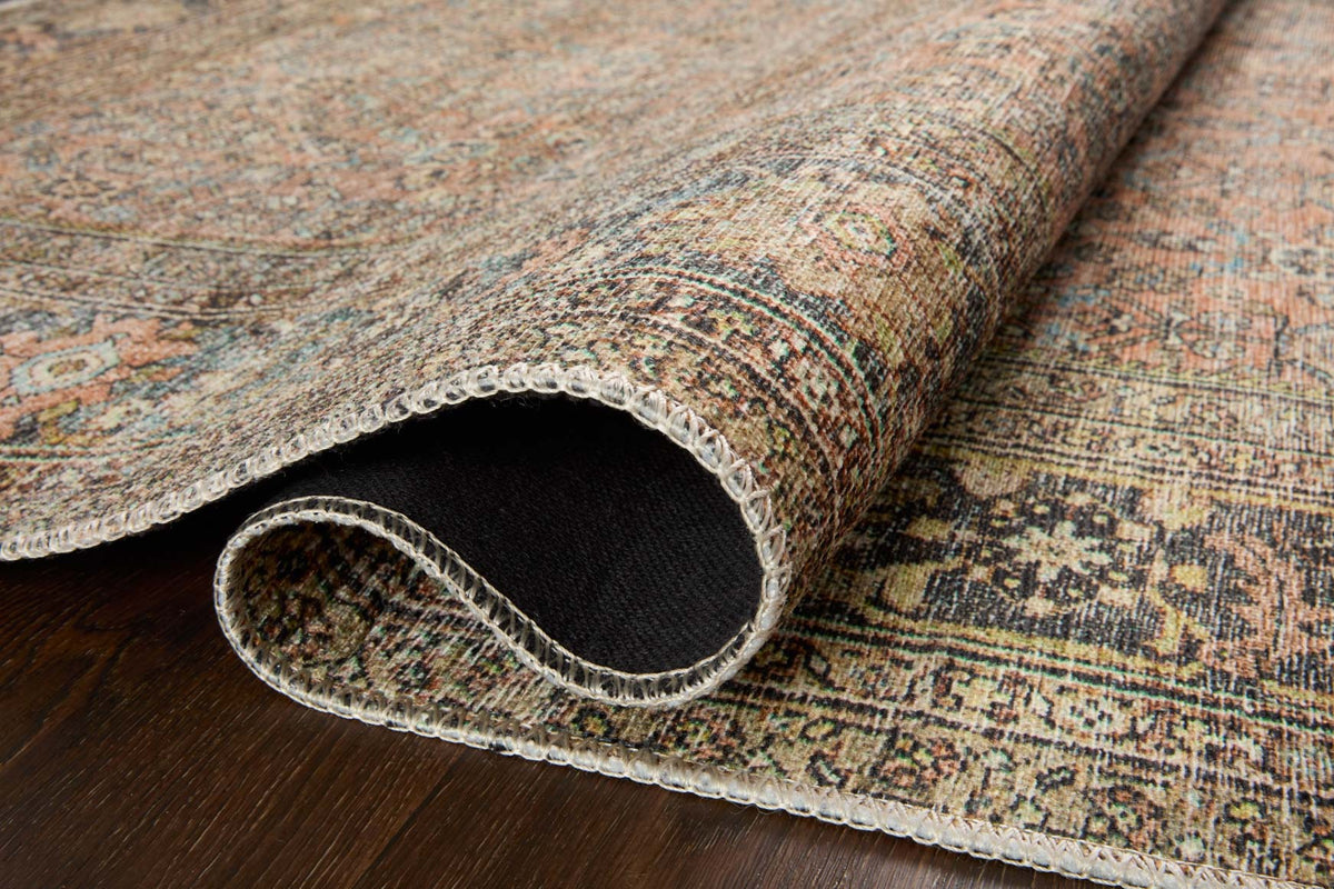 Rug edge close-up showing textured pile and woven border in muted beige, teal, and terracotta