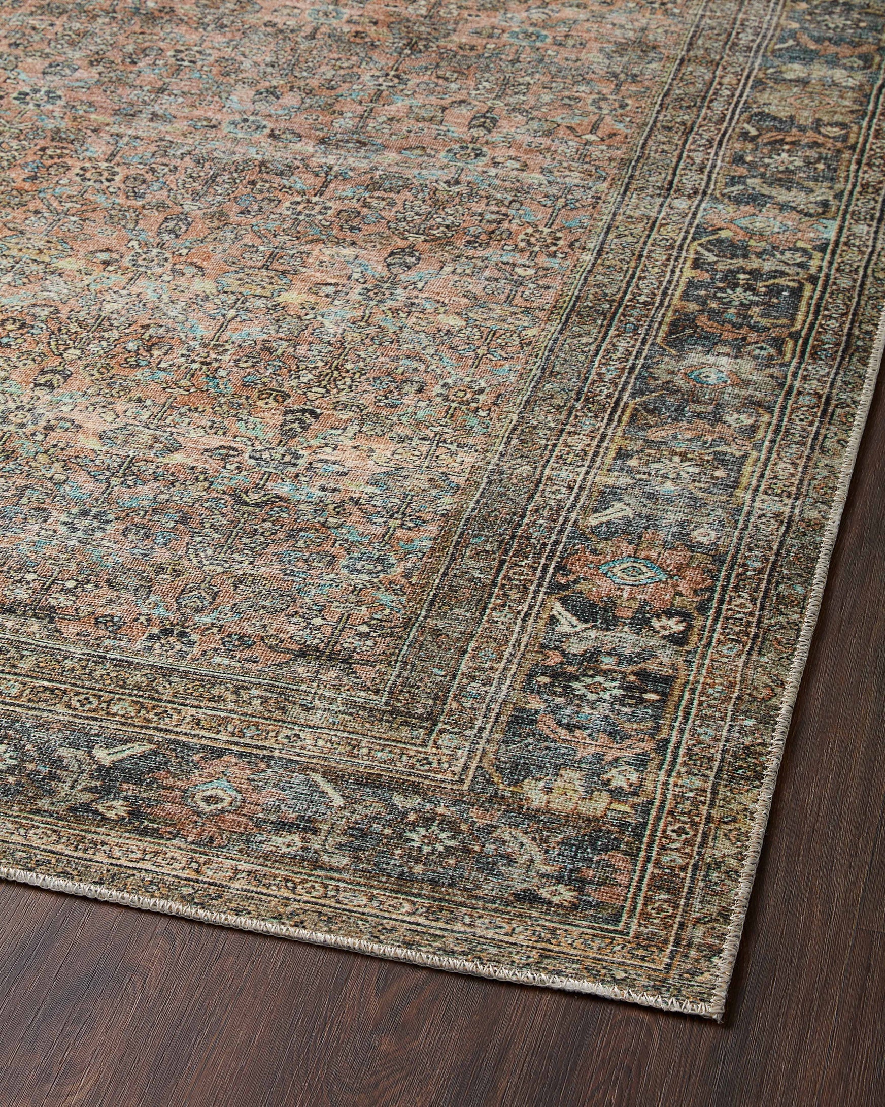 Close-up of traditional rug field pattern and border lines in terracotta, teal, and beige