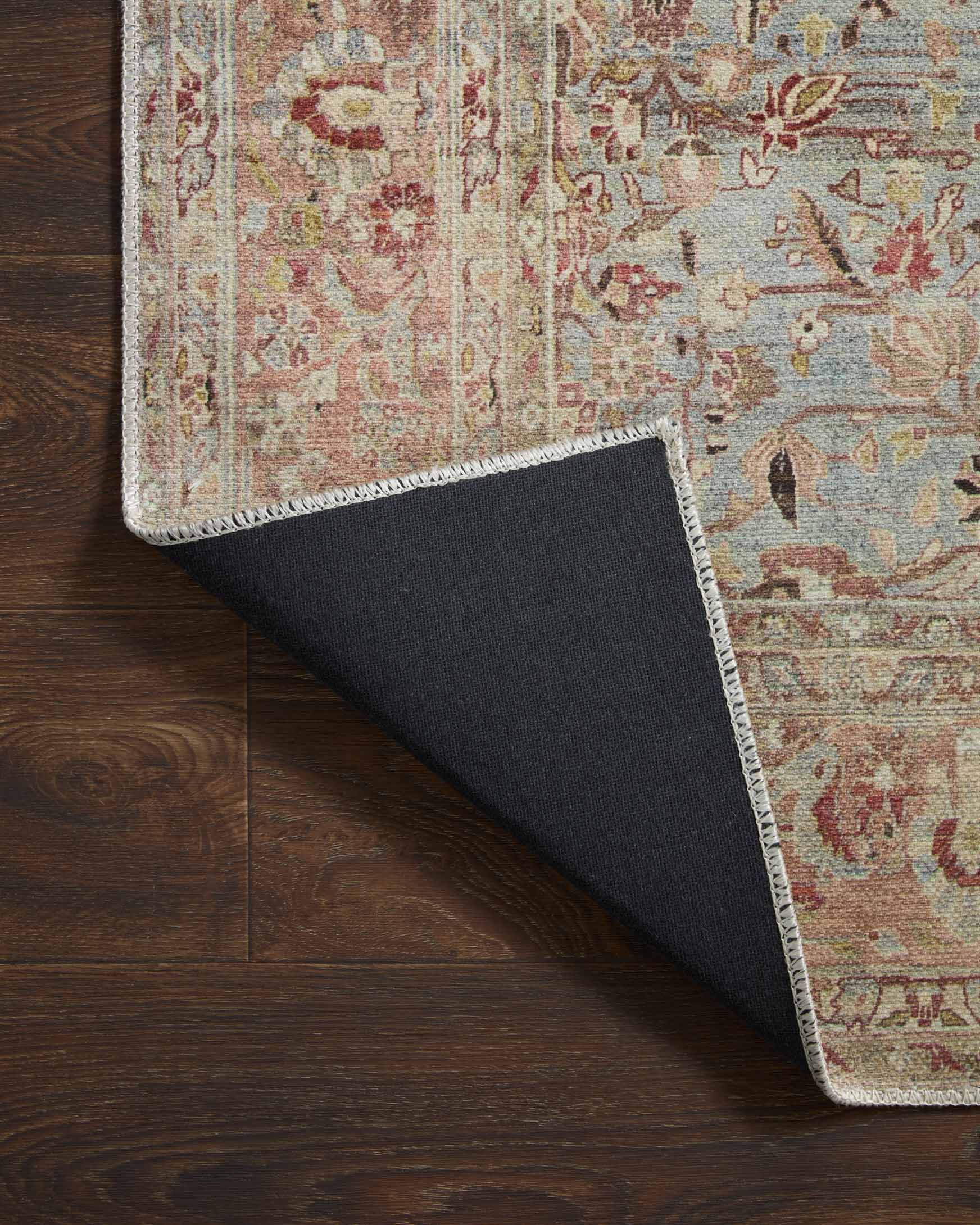 Corner lifted to show rug underside backing in dark gray with light border trim.