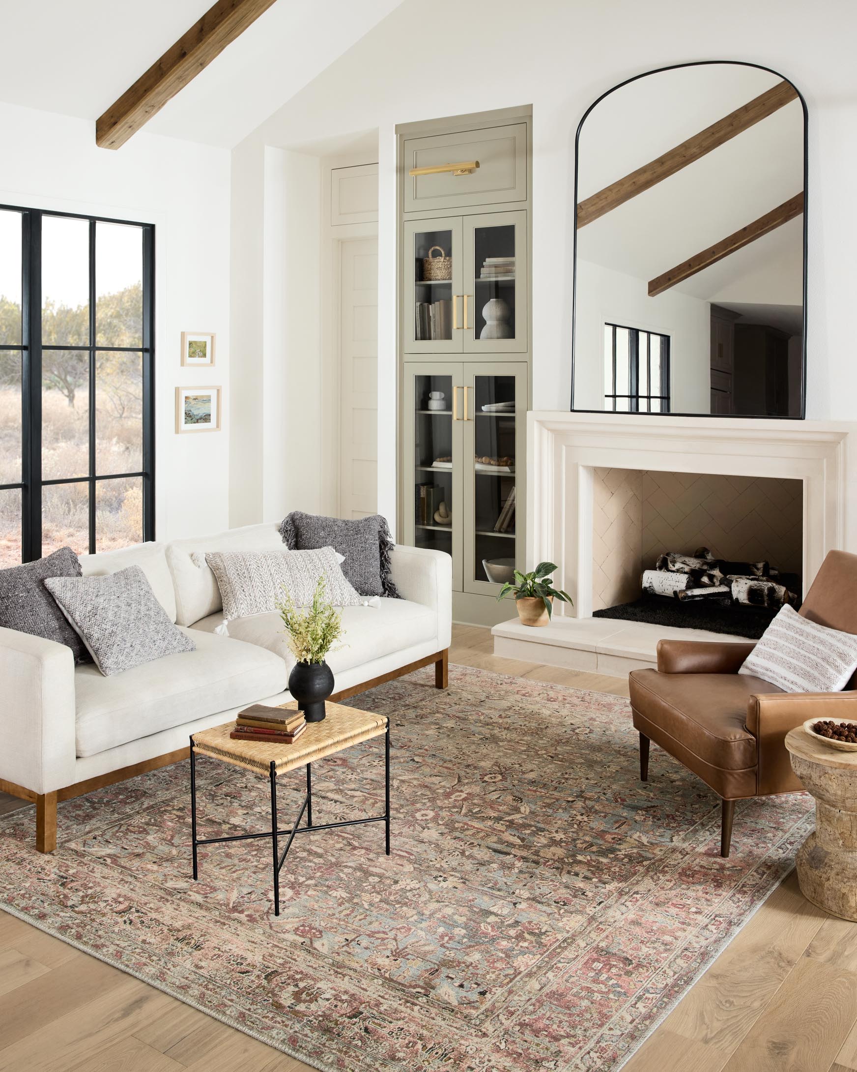 Ornate patterned area rug in ocean and clay tones, placed on a floor.