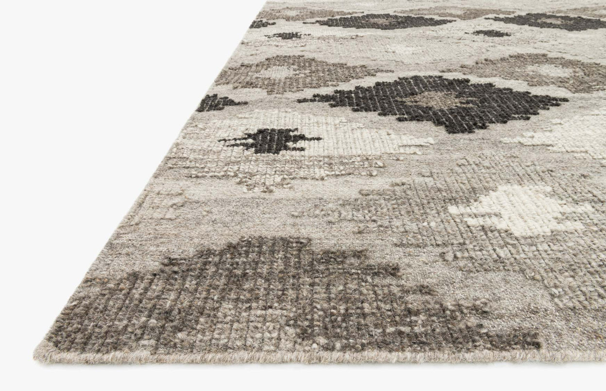 Hand-woven rug with grey/charcoal diamond motif, corner view