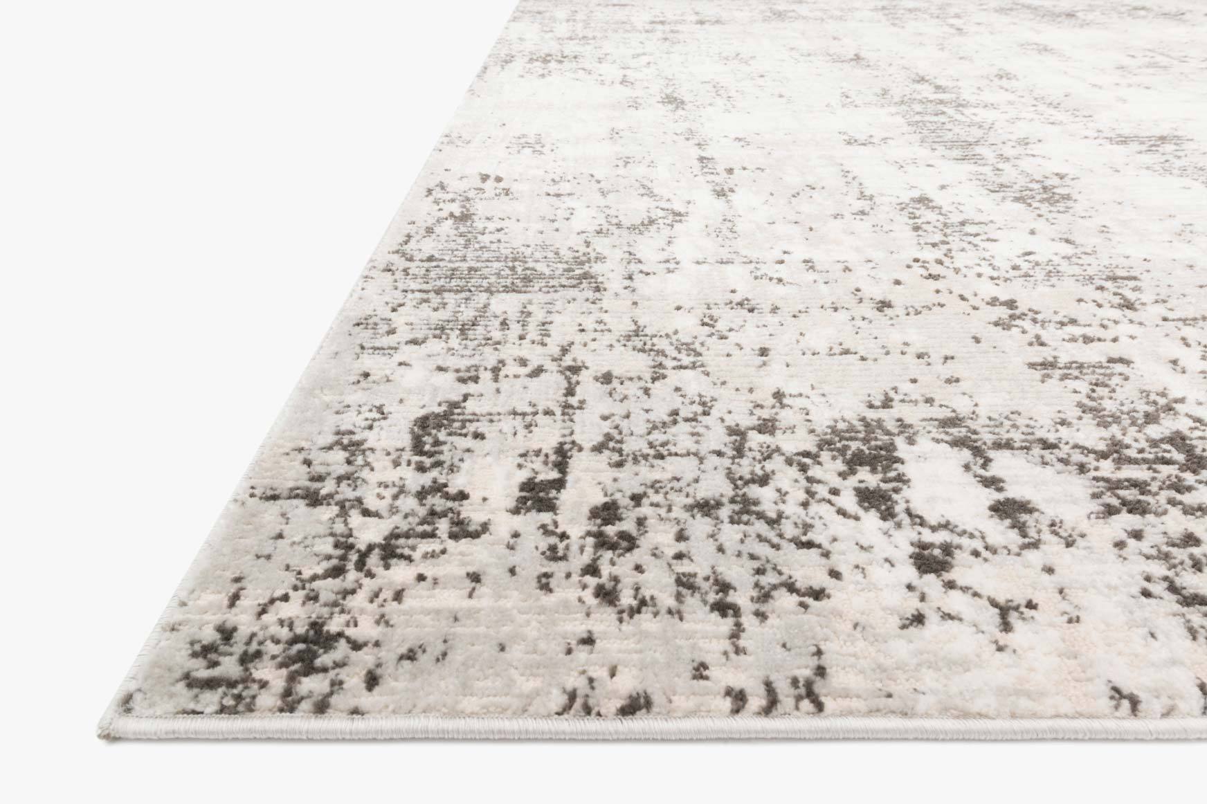 Power-loomed rug corner view, silver background with scattered graphite brushstroke pattern