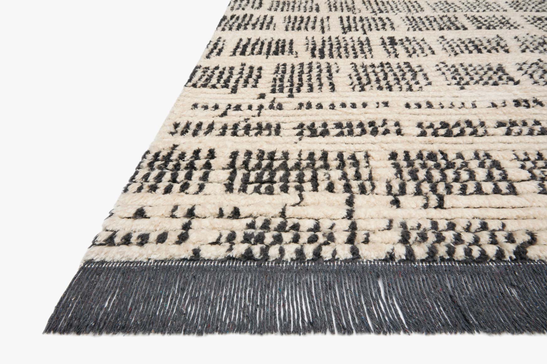Cream and charcoal rug corner detail with short fringe edge and textured stripe pattern