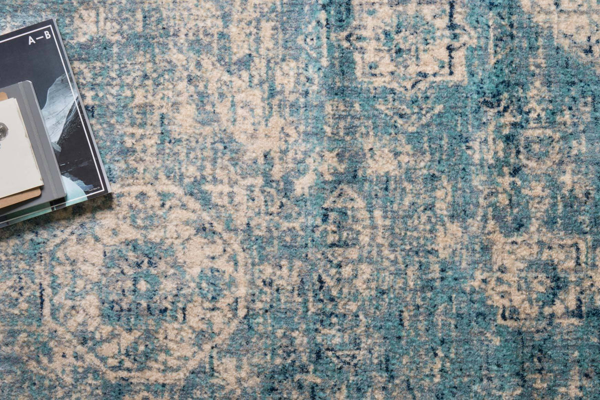 Light blue and ivory rug surface with distressed geometric motifs, textured weave