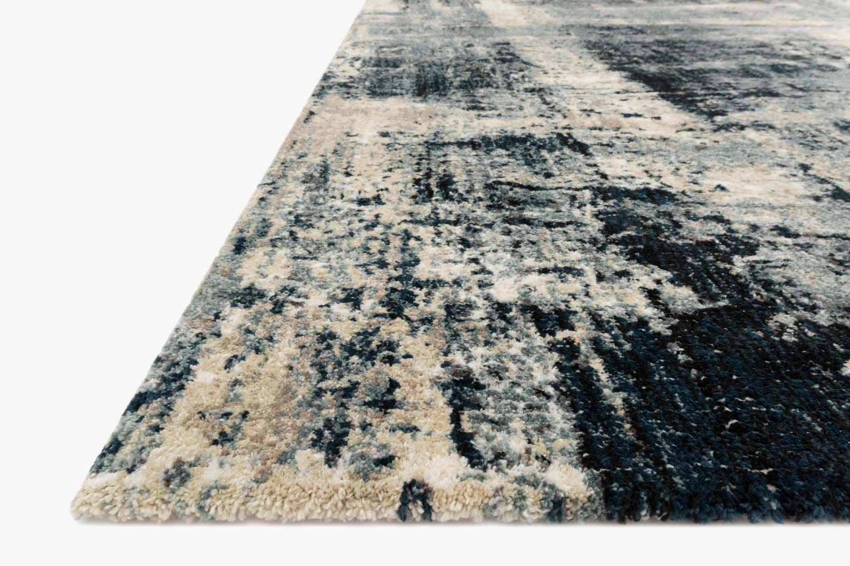 Power-loomed area rug corner view in abstract navy and dove with textured pile.