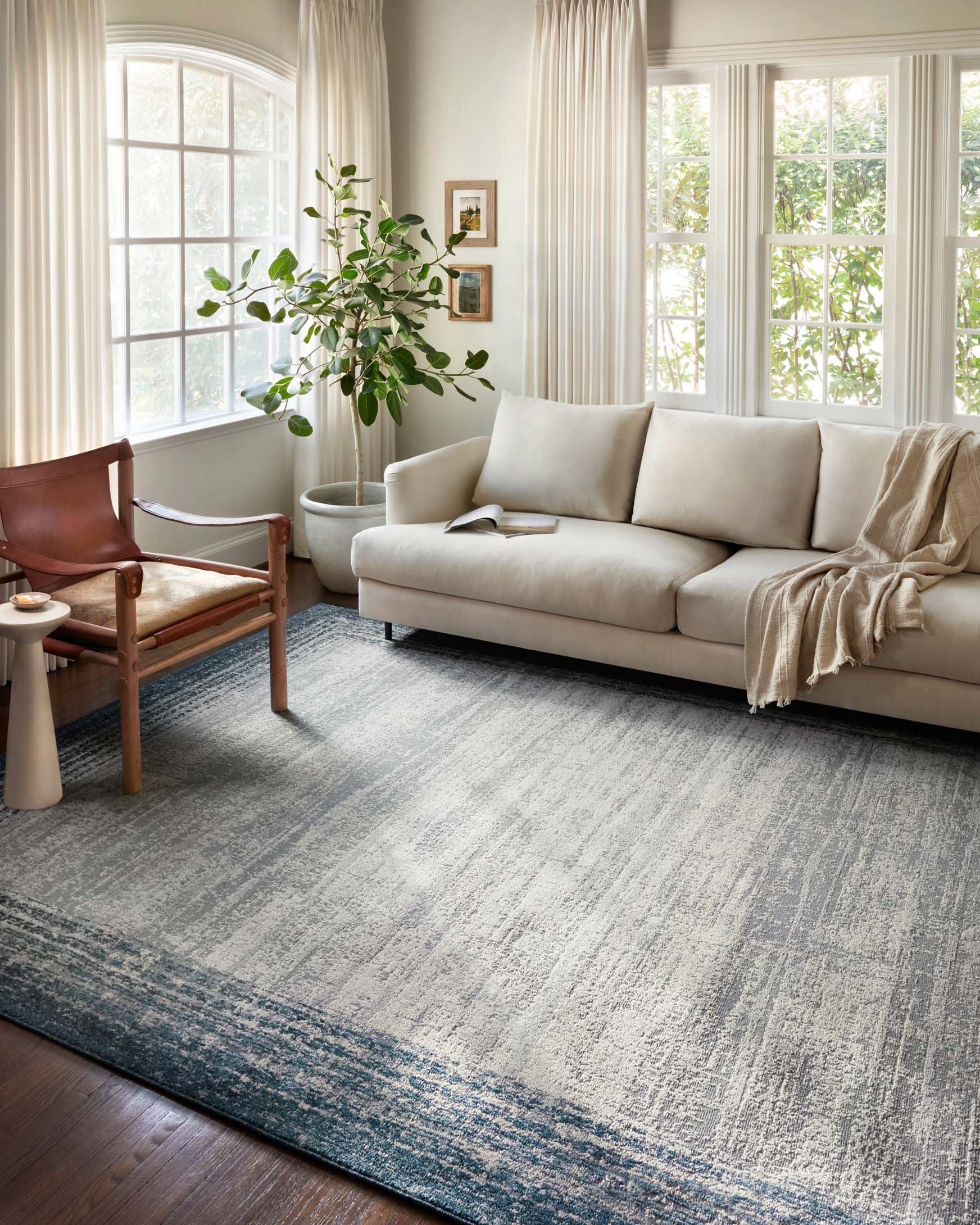 Pebble-and-blue abstract bordered area rug with distressed texture, low pile