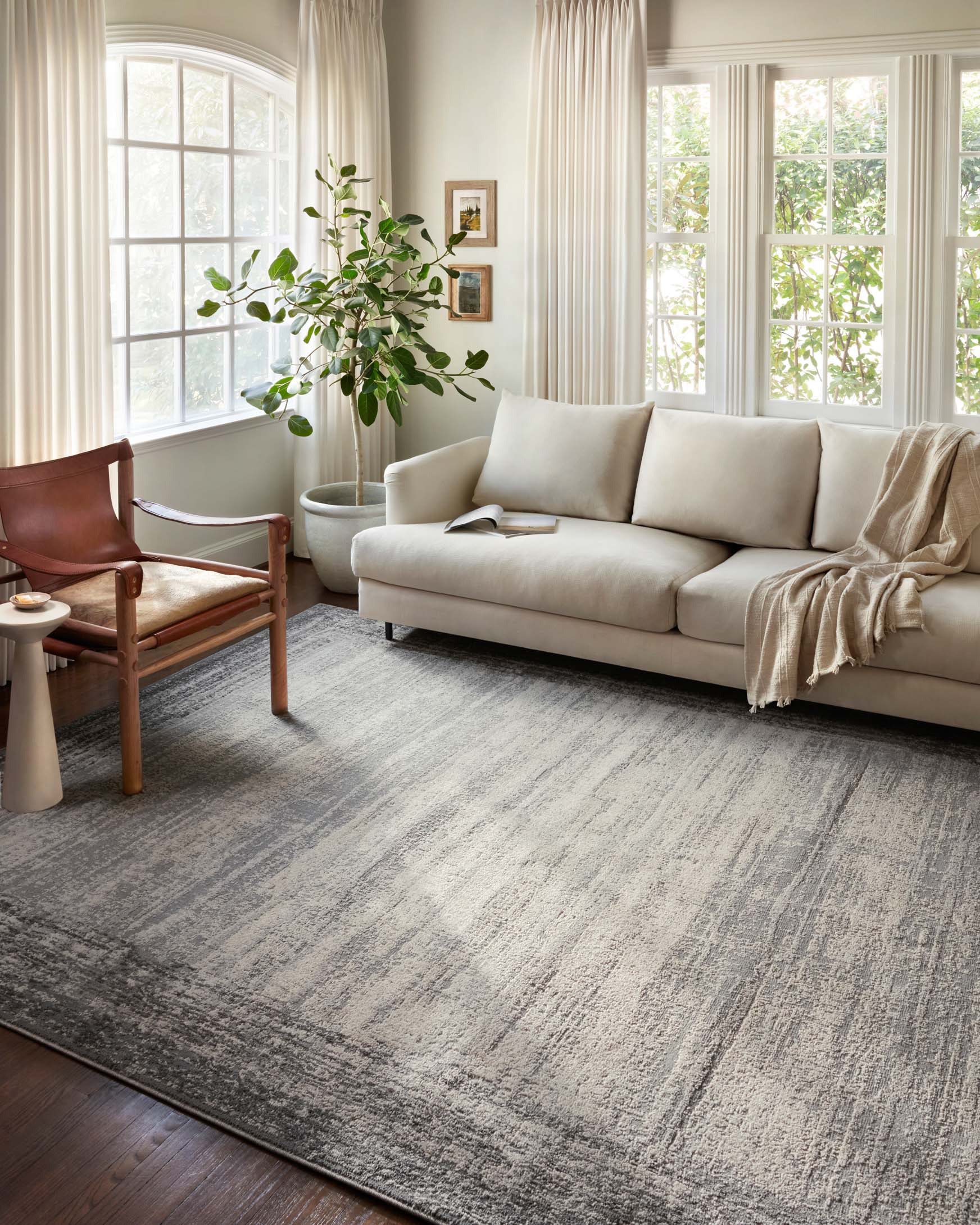 Rectangular pebble-and-charcoal area rug with distressed lines and low-pile texture