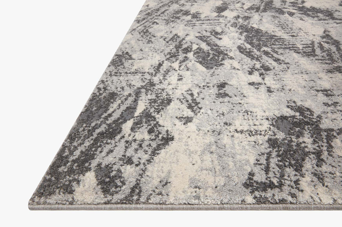 Corner view of stone and pebble area rug with distressed abstract motif