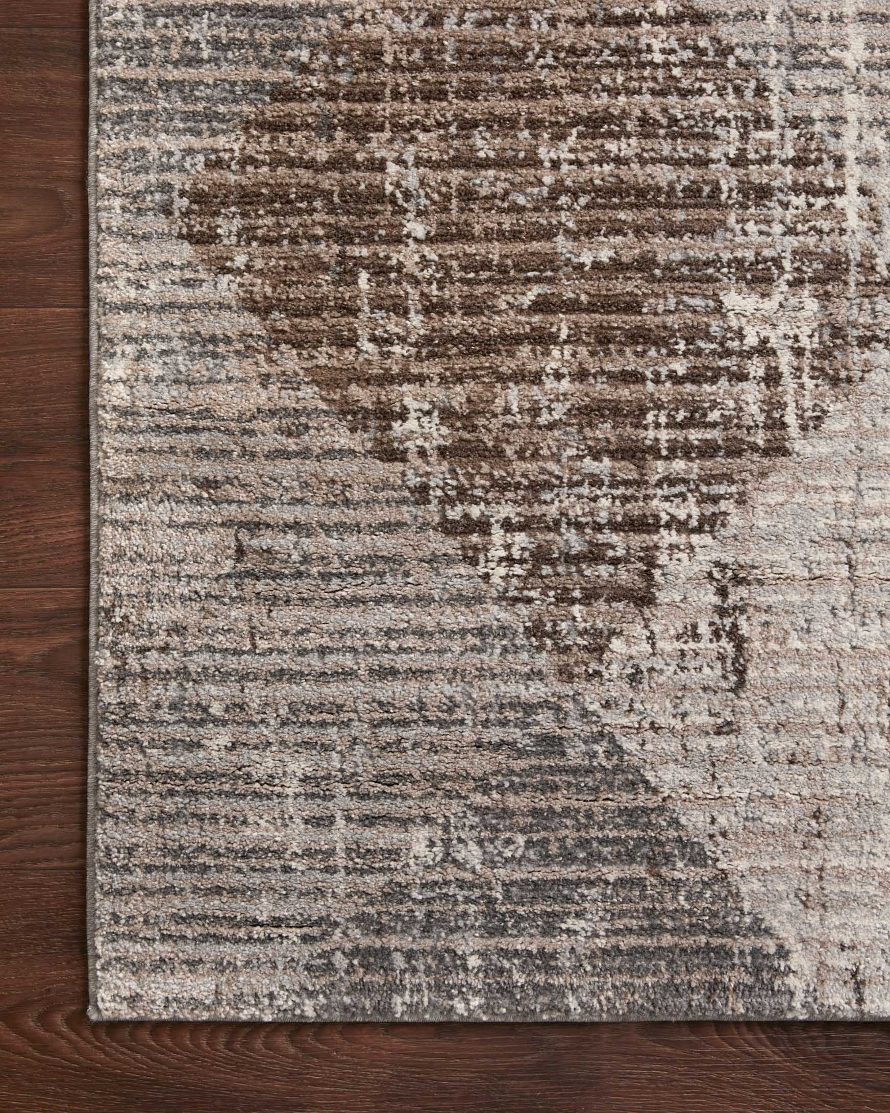 Rug corner on wood floor, featuring textured geometric pattern in stone and bark