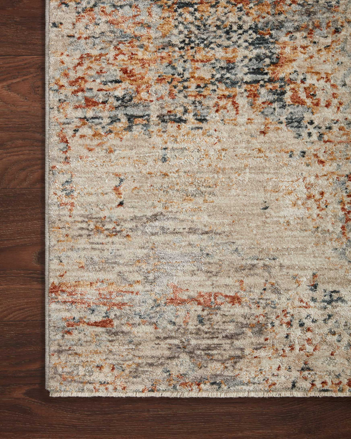 Close-up of rectangular rug texture with distressed abstract pattern in sand, blue-gray, rust