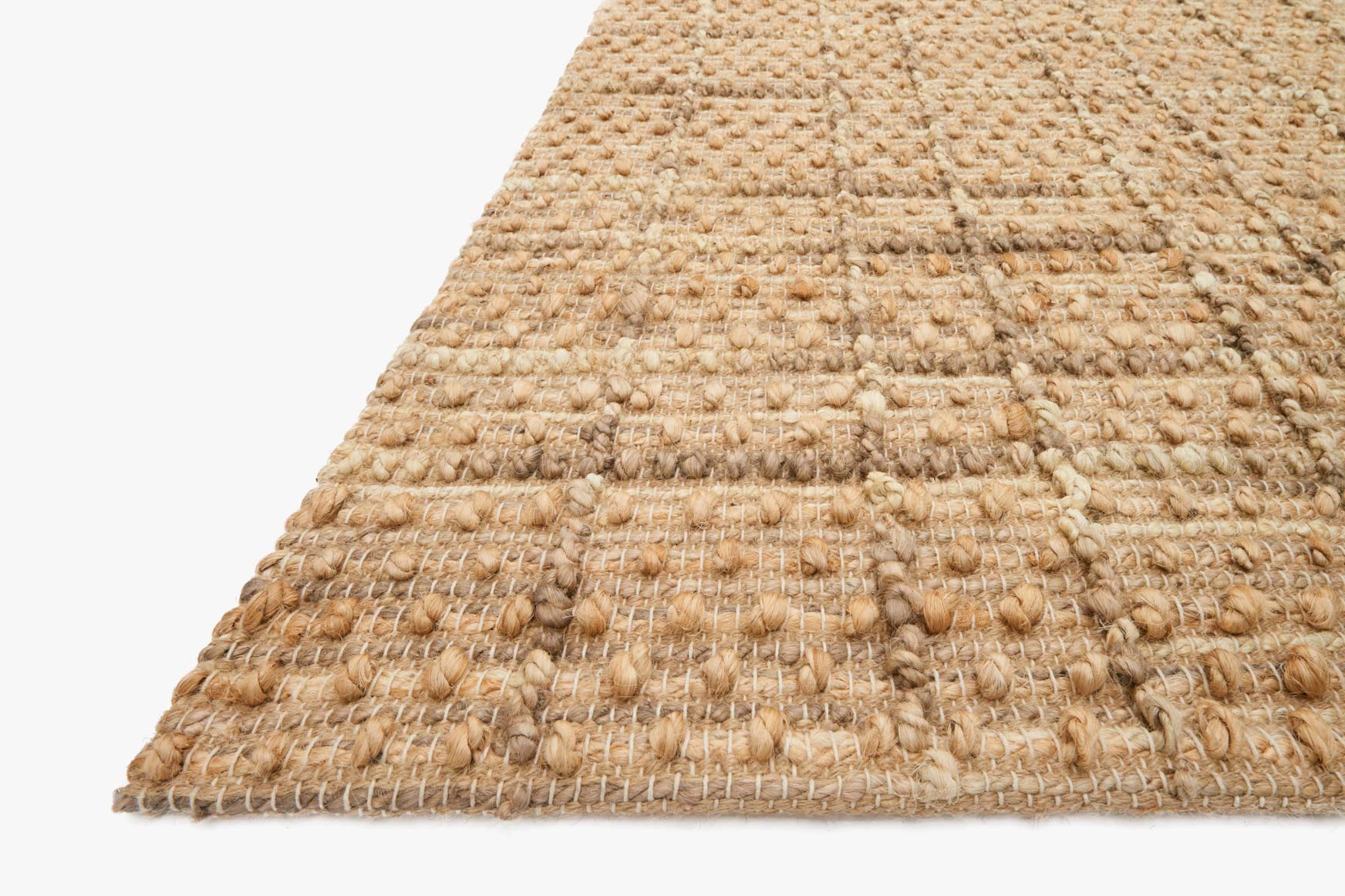 Natural hand-woven rug corner detail with looped texture and frayed fringe edge.