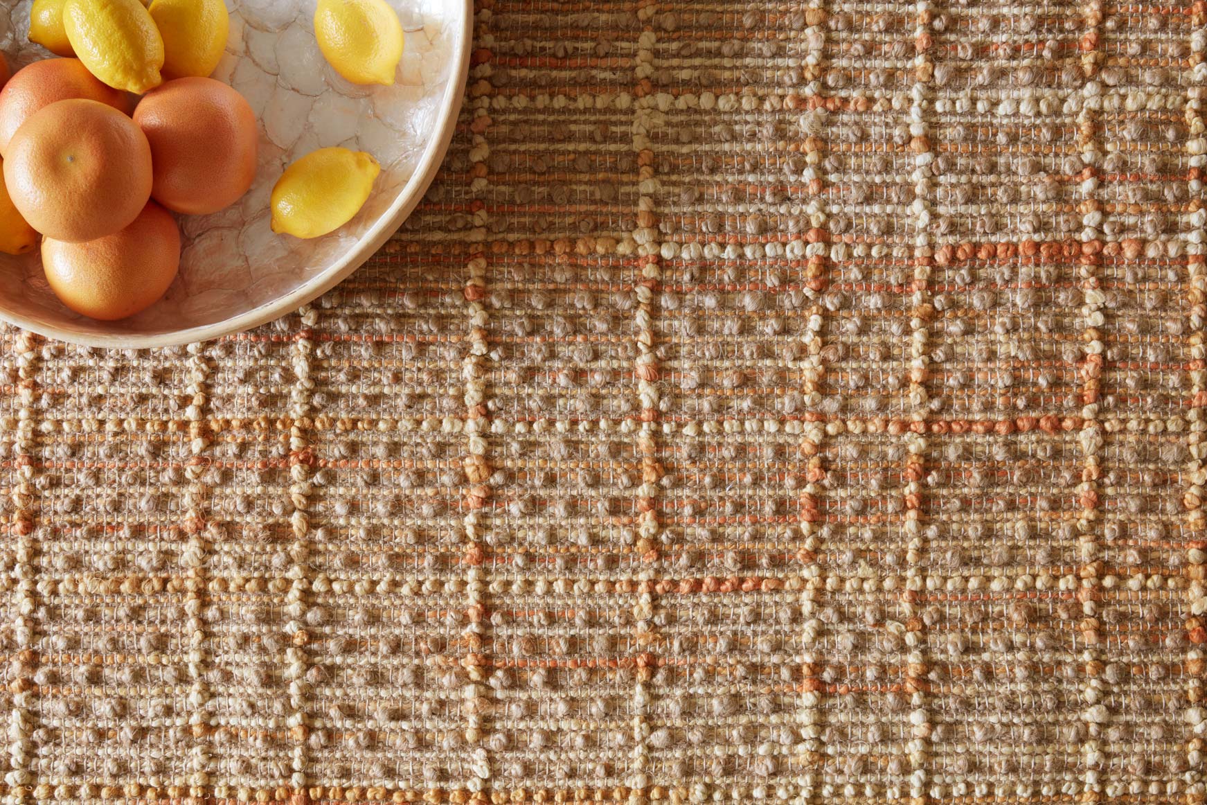 Hand-woven rug close-up with tangerine, cream, and brown speckled texture