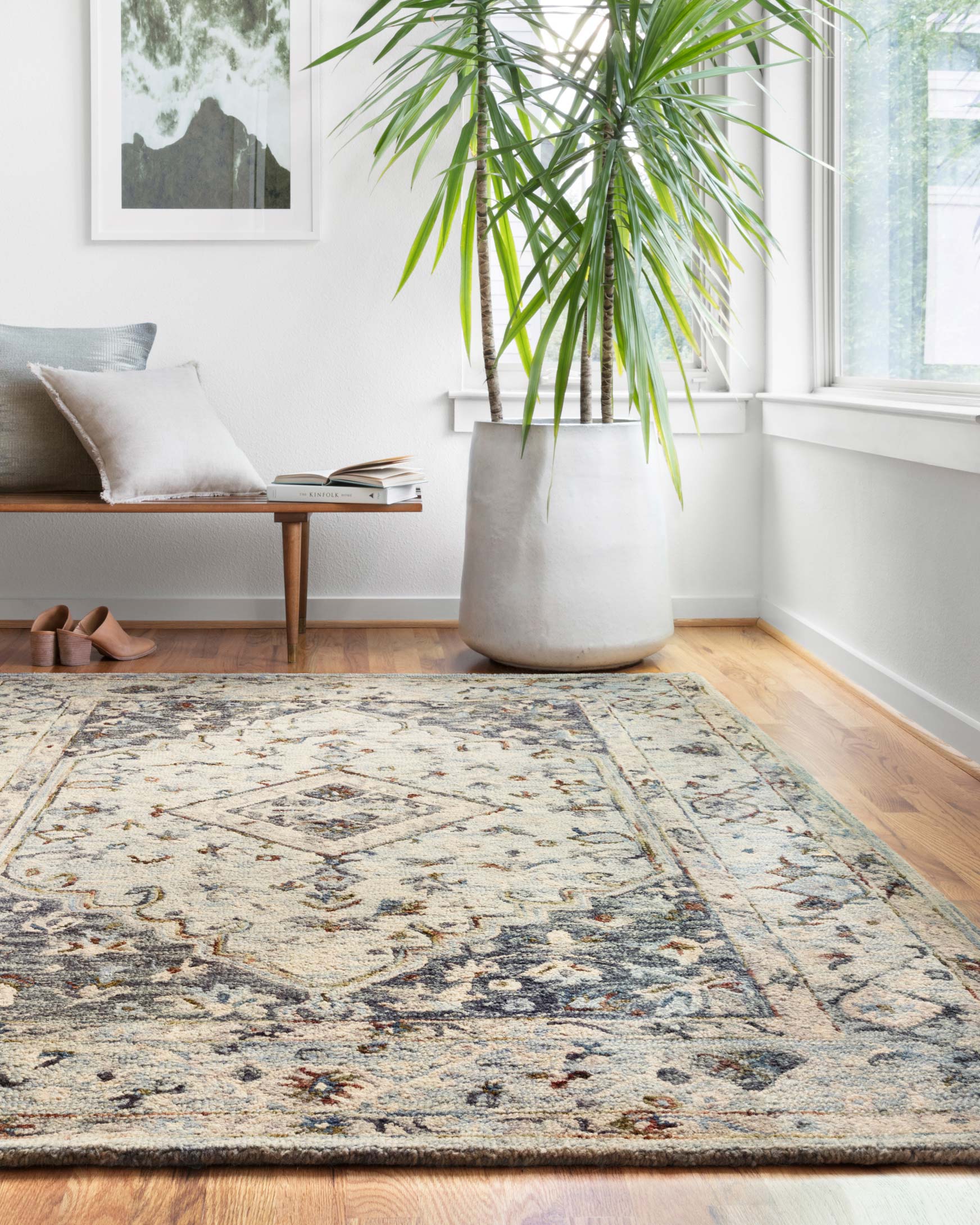 Traditional area rug in light blue and blue with ornate border, laid on floor.