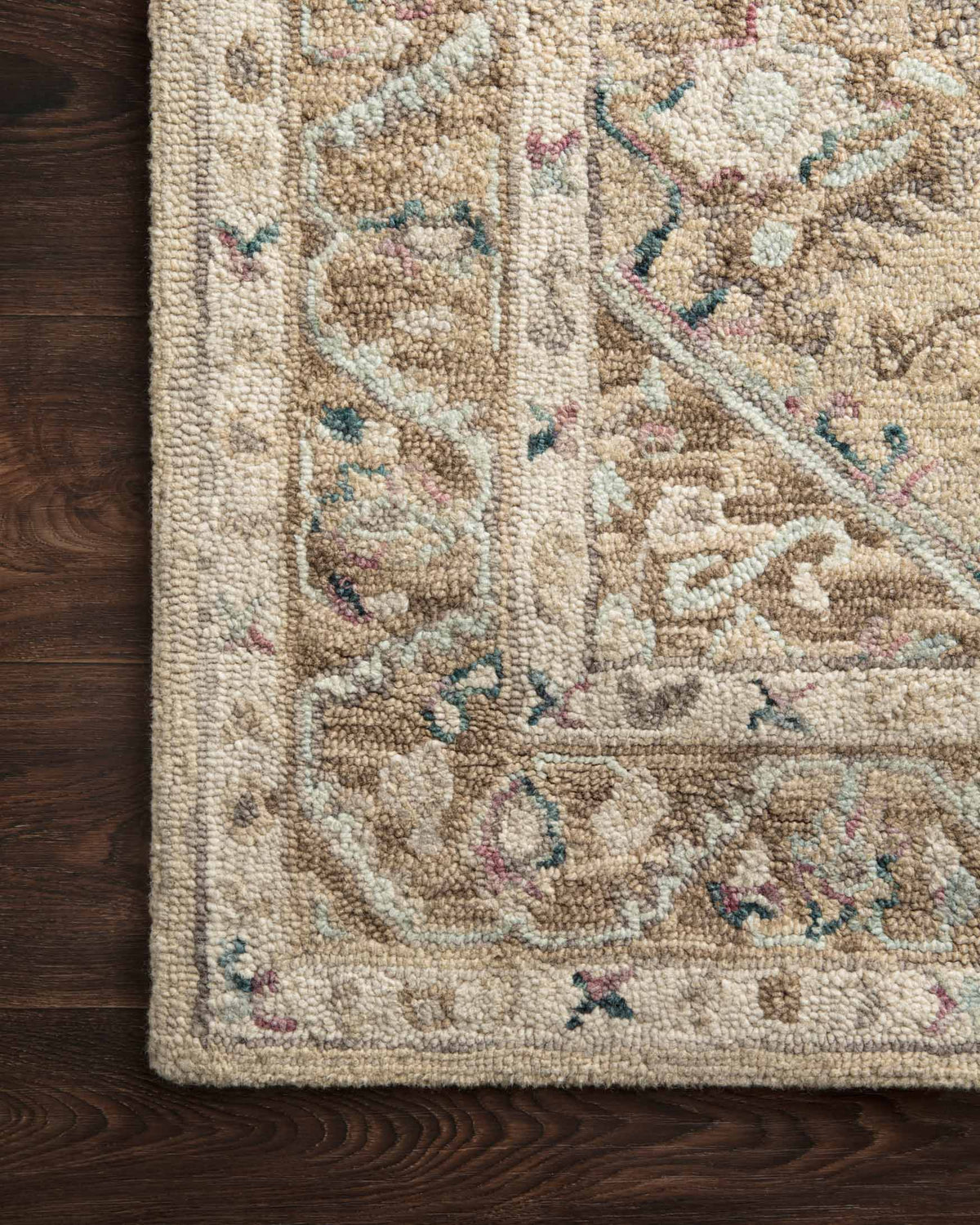 Textured close-up of beige and ivory hooked rug with multicolor accents on the pile.