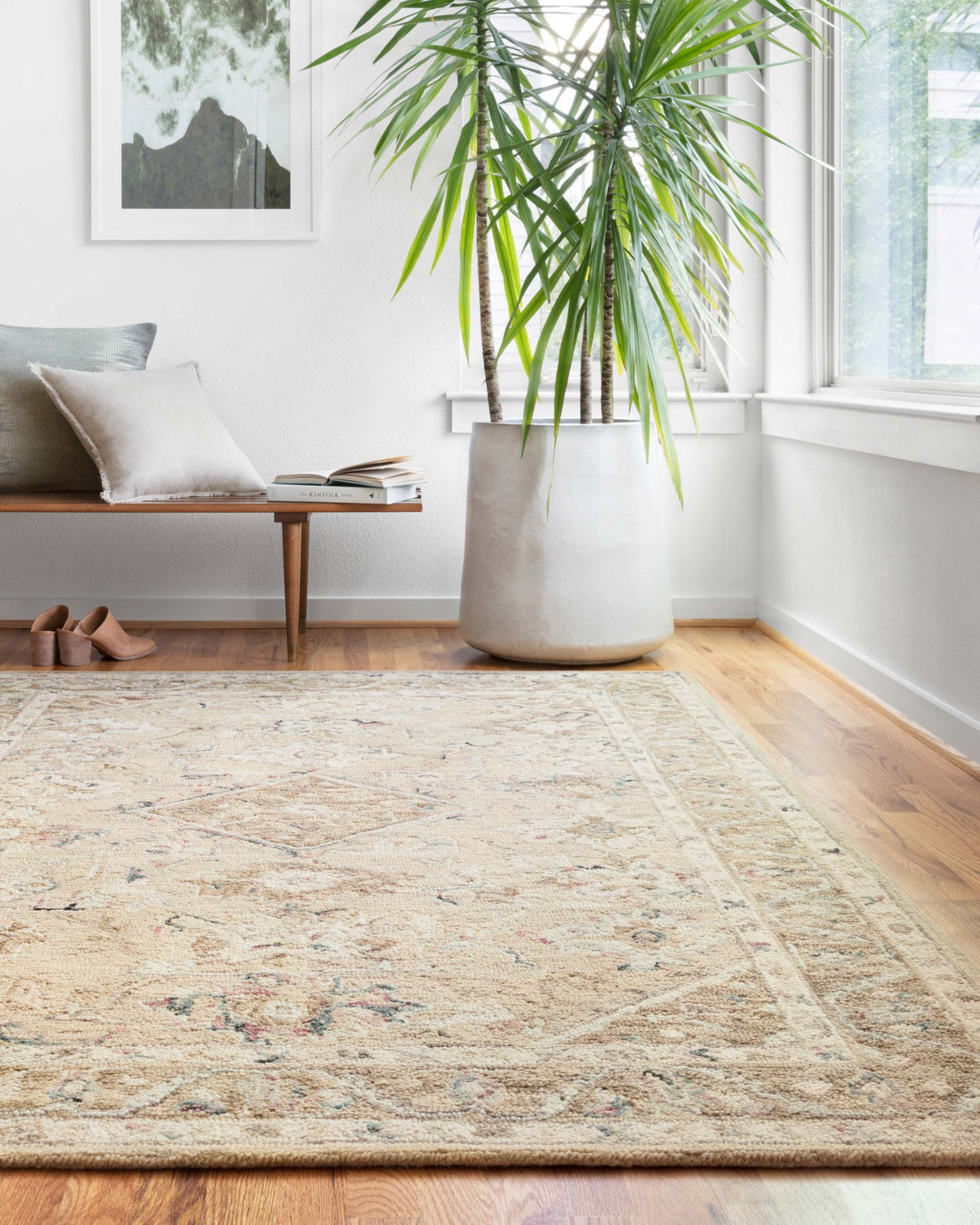 Beige and ivory traditional hooked rug with faded blue, green, and pink patterning.