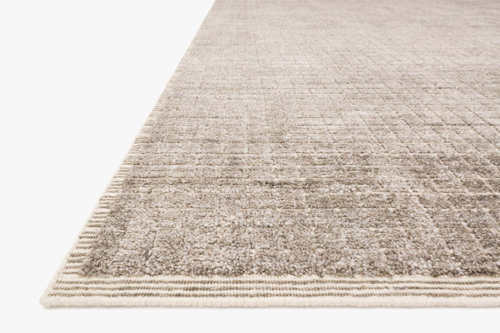 Contemporary hand-loomed rug in stone beige, angled view with low-profile textured border