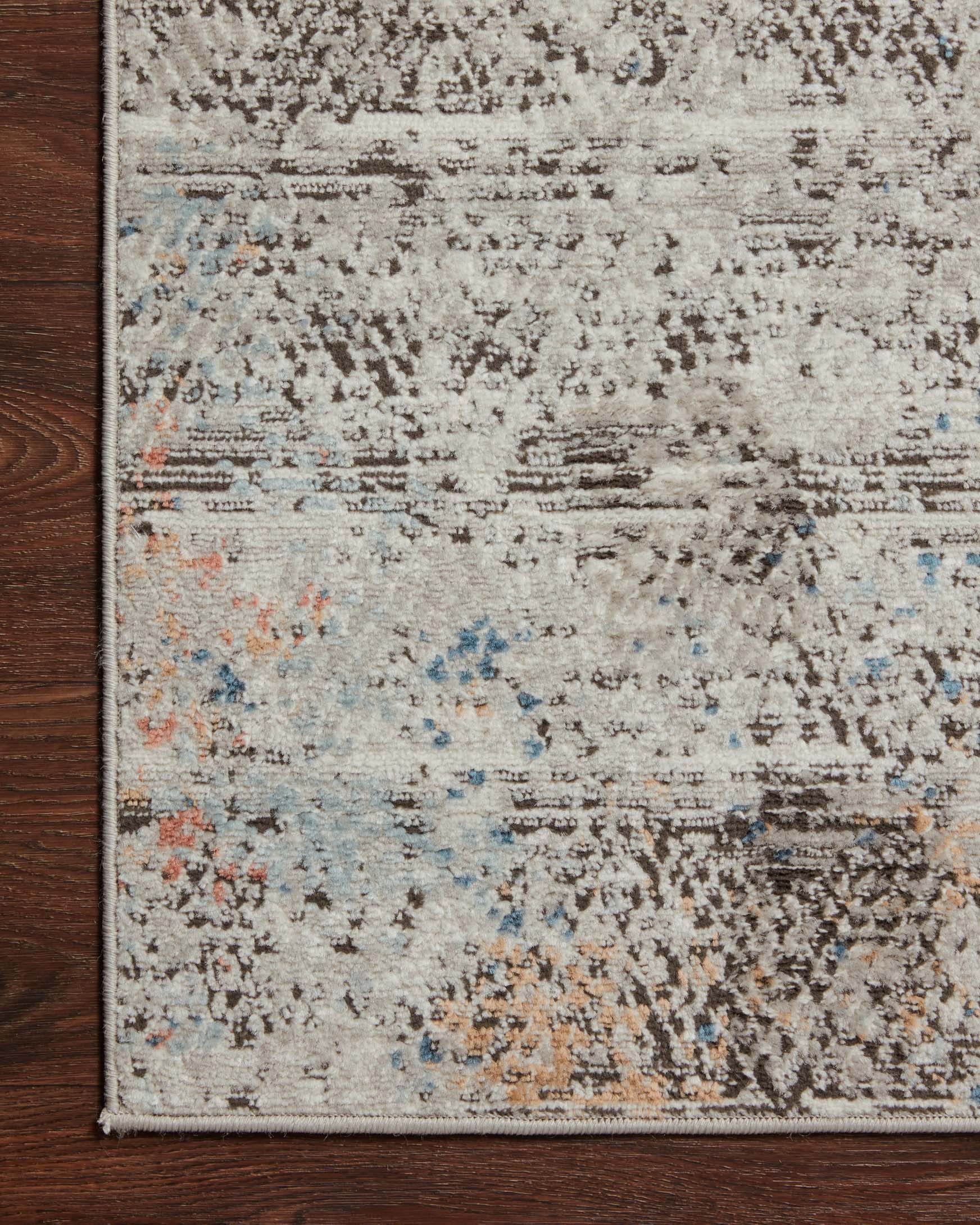 Grey abstract rug corner with distressed texture and blue orange speckled details