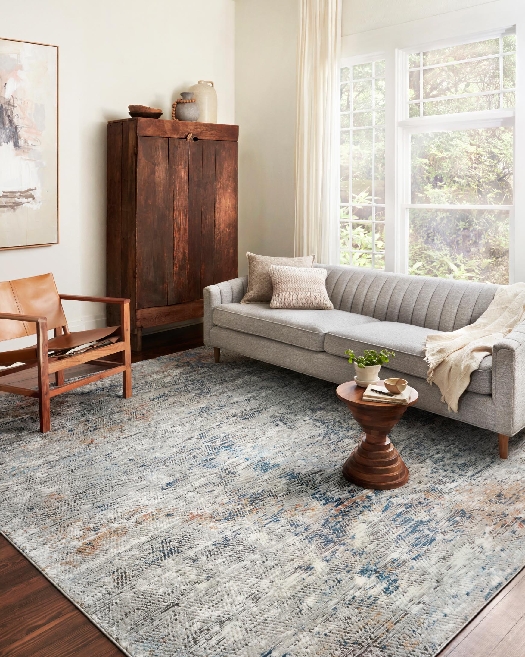 Contemporary grey rug with abstract distressed design in blue and orange on hardwood floor