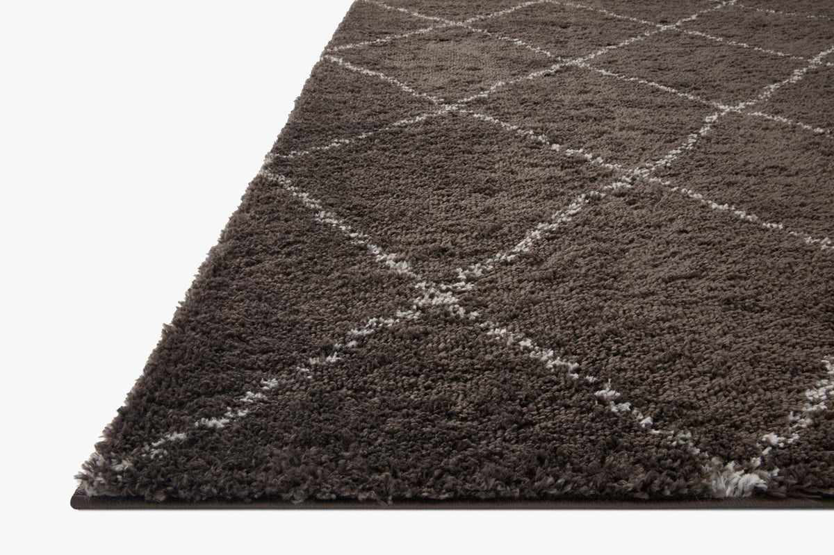 Corner close-up of dark shag rug with light grey diamond trellis pattern.