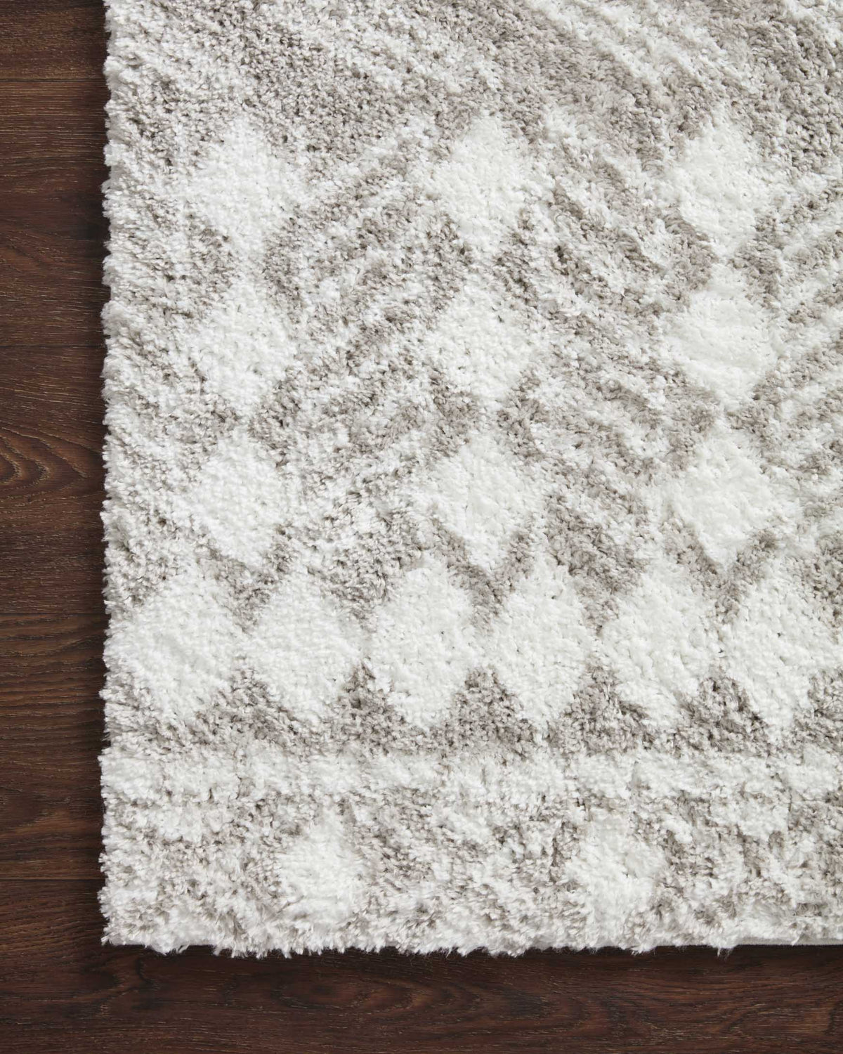 Grey and white shag rug with textured pile and subtle geometric pattern on wood floor.