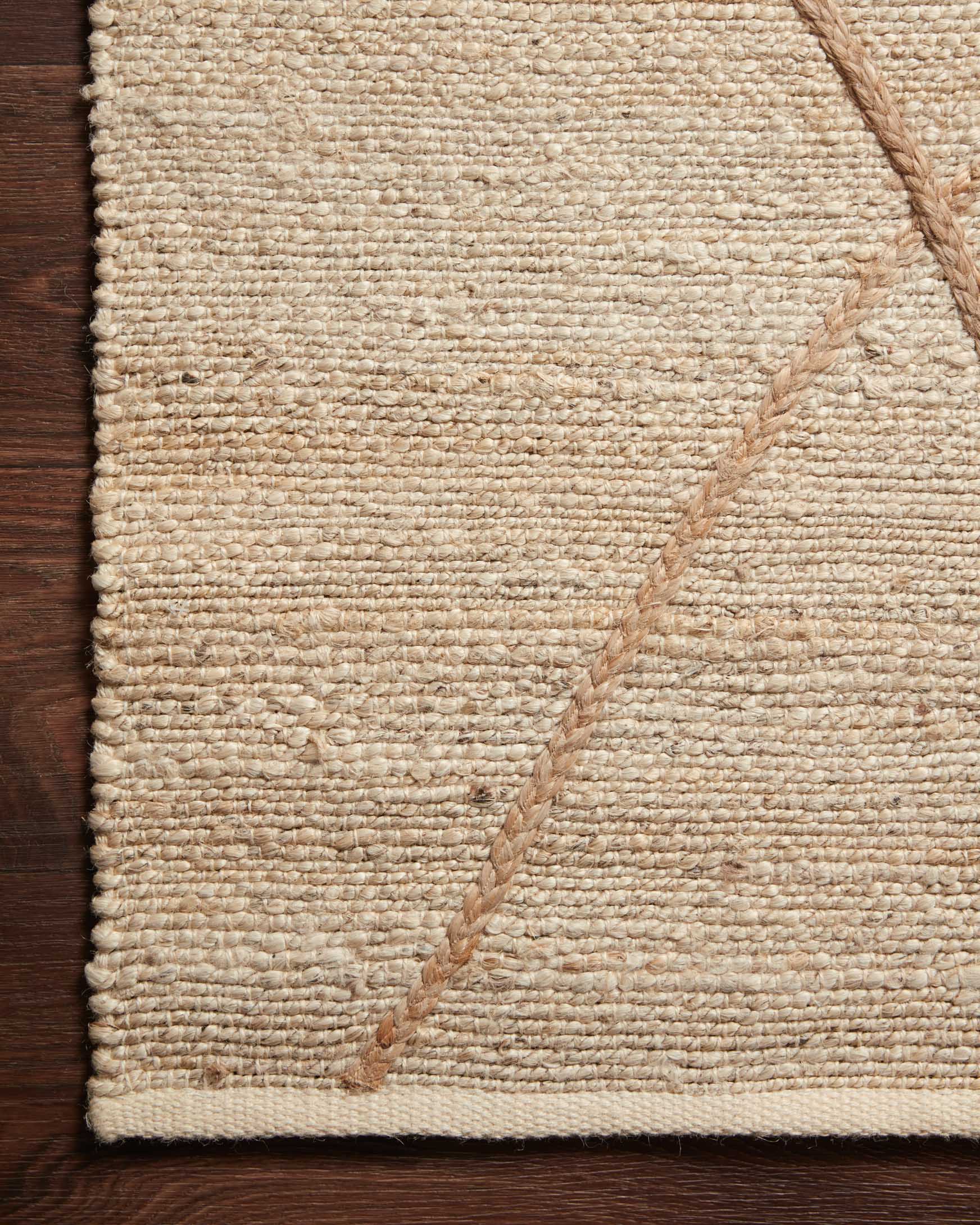 Ivory hand-woven rug corner with tan diamond lattice and stitched border seam detail