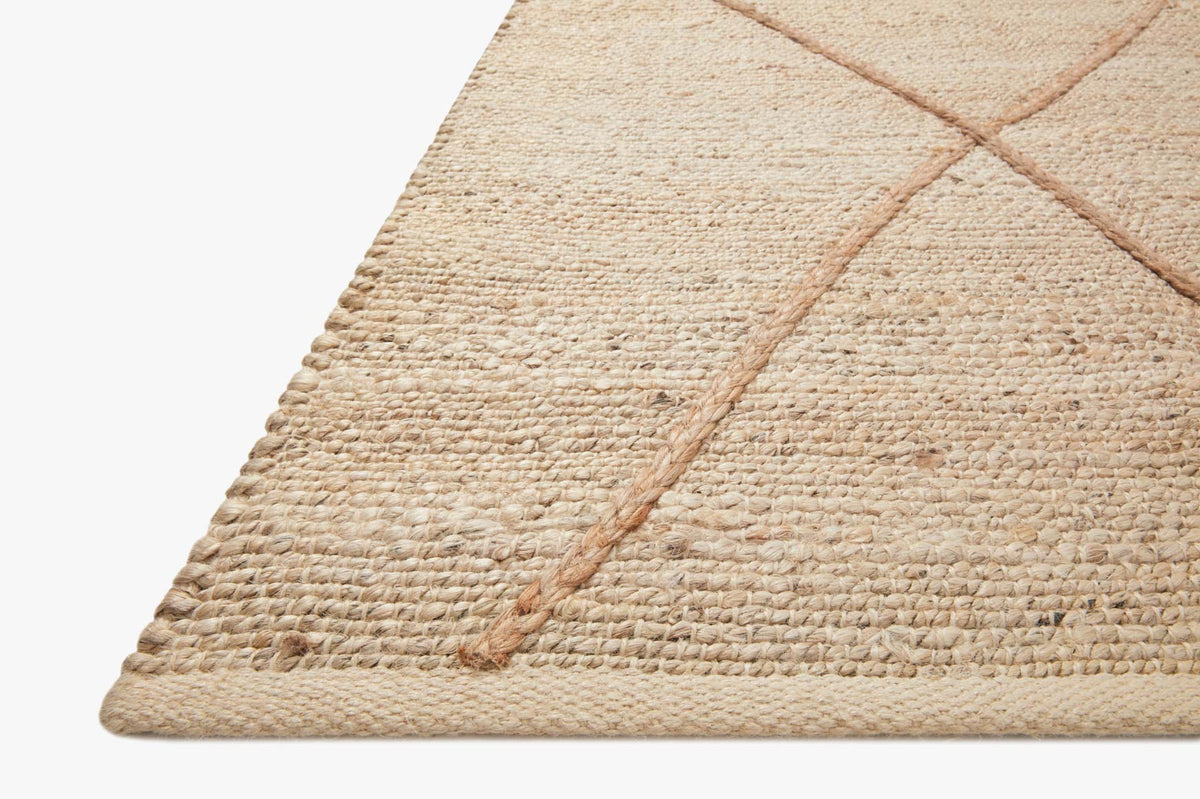 Corner of hand-woven rug in ivory with tan lattice lines and short fringe edge