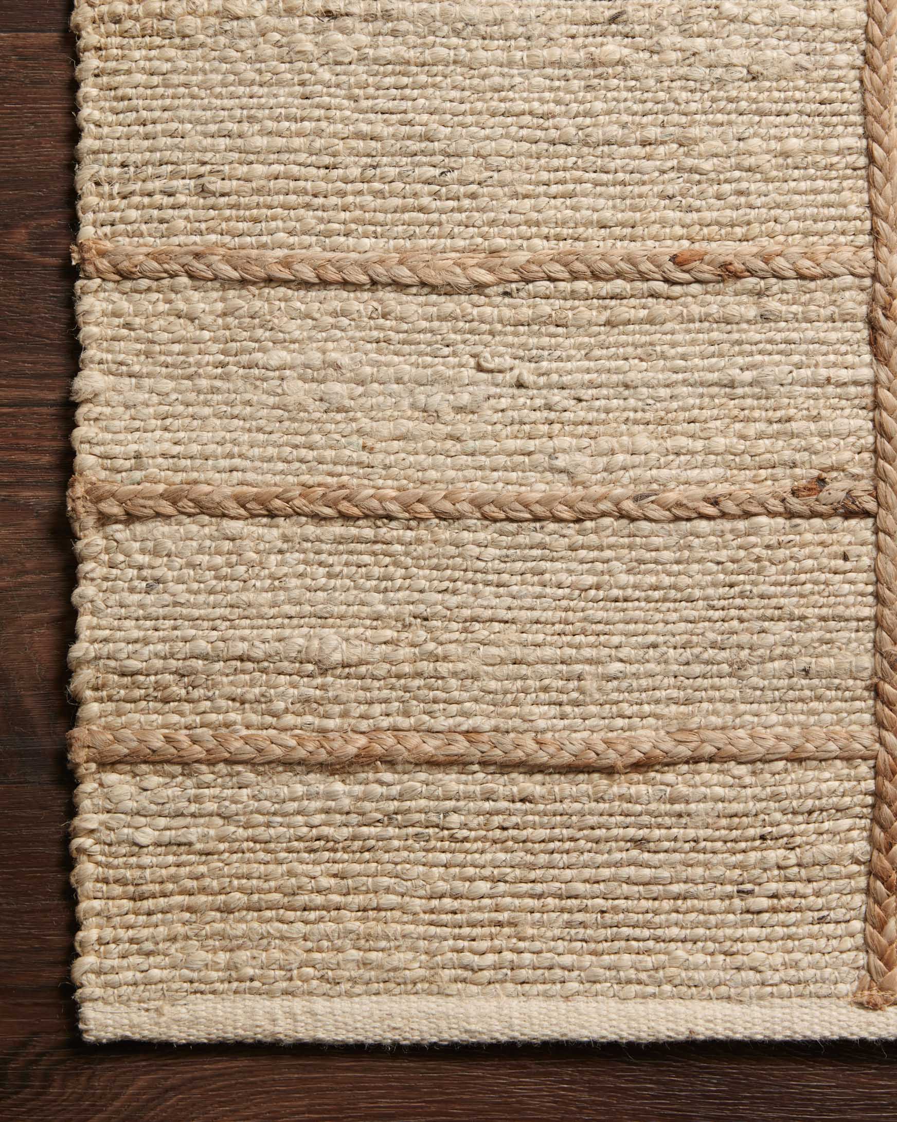 Ivory and natural hand-woven rug surface with stitched bands and speckled texture.