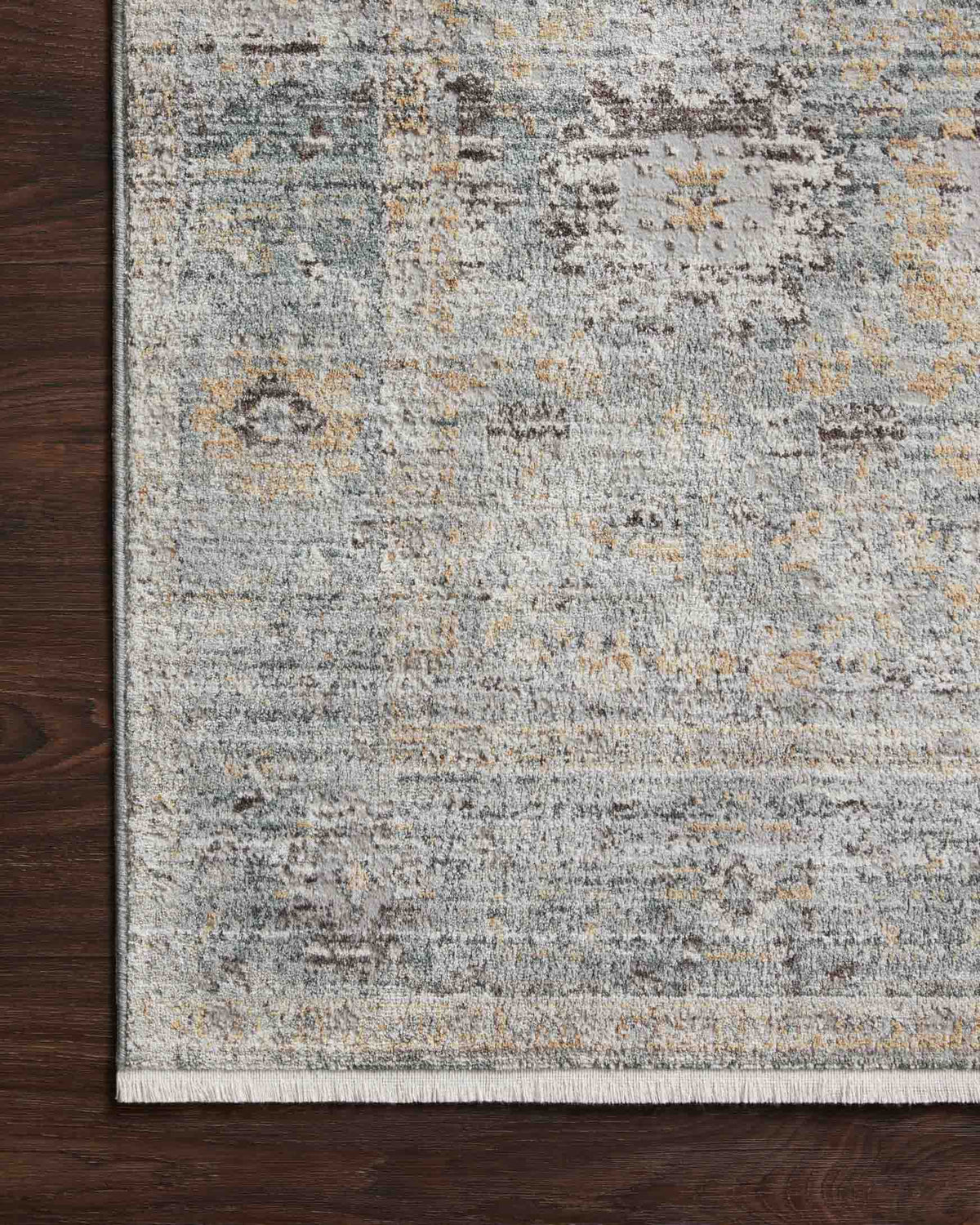 Teal and gold rug with distressed pattern and trimmed edge, close-up woven texture.