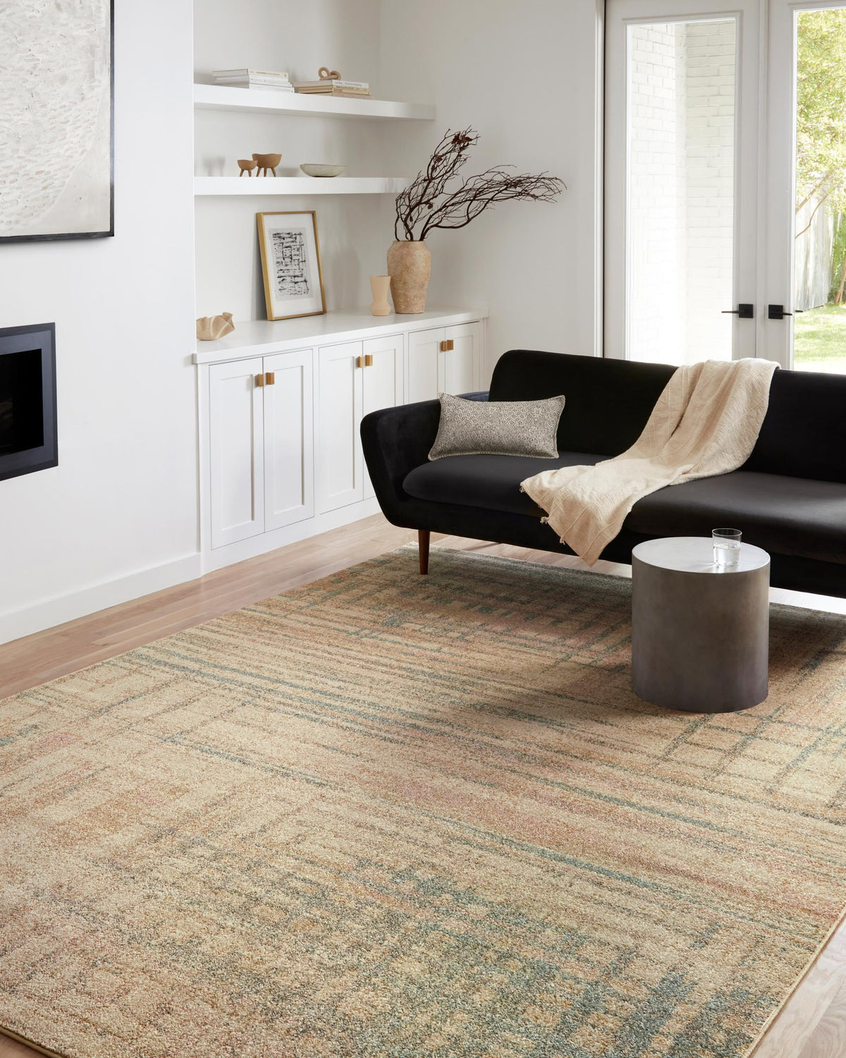 Beige area rug with textured abstract pattern in teal and rust accents.