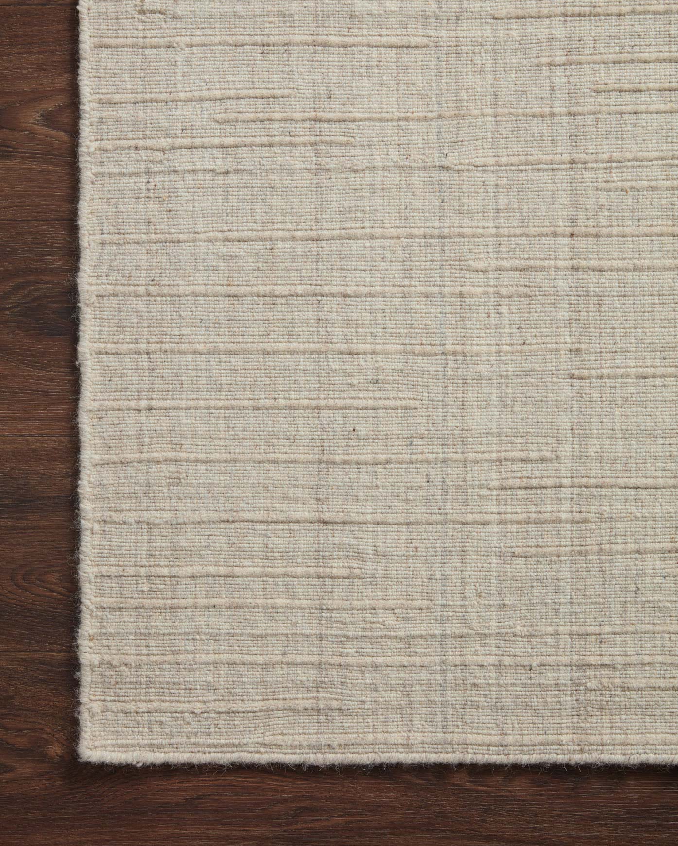 Stone hand-woven rug edge with subtle border and fringed selvage, close-up