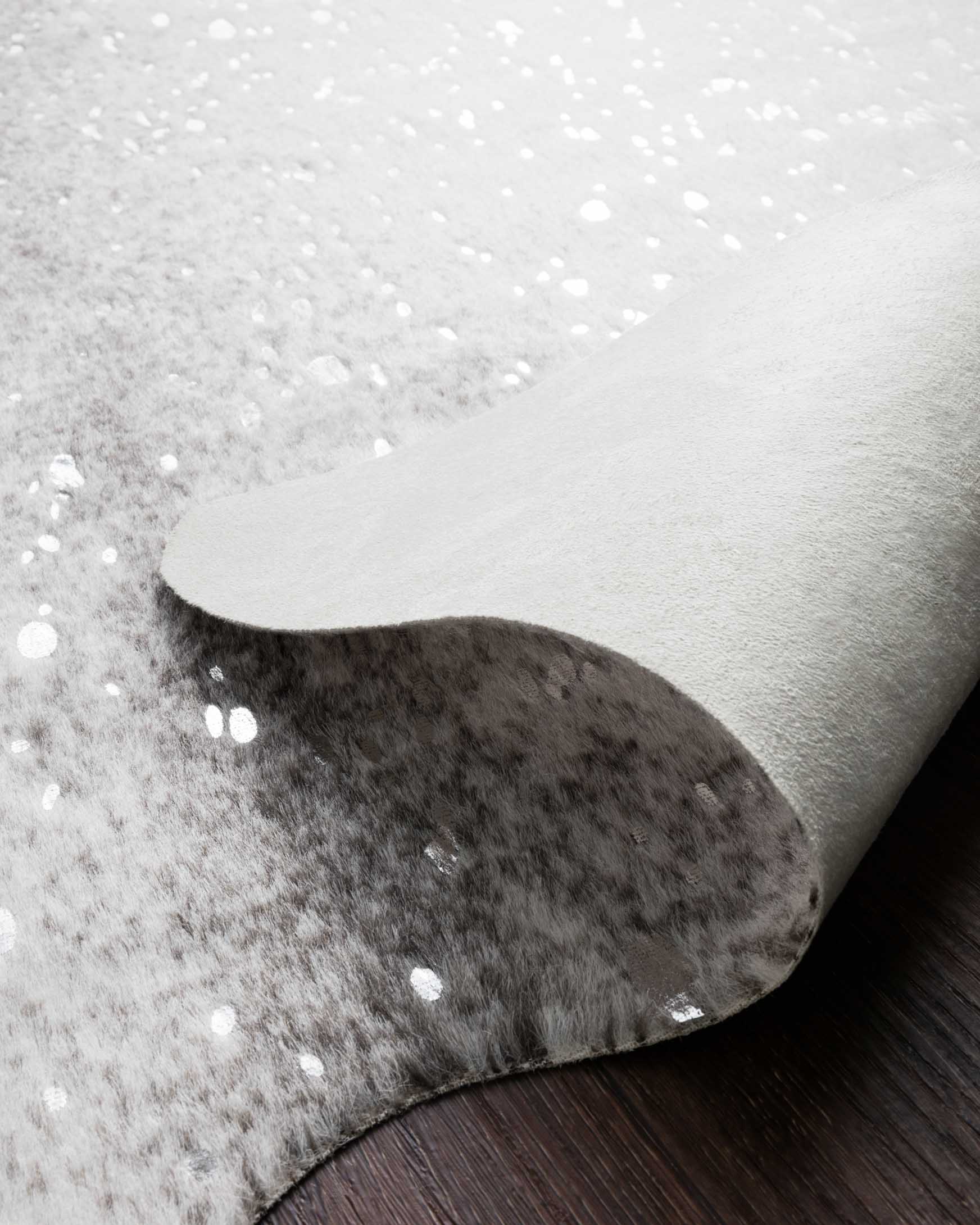 Grey and silver speckled rug close-up showing curved edge and plush texture