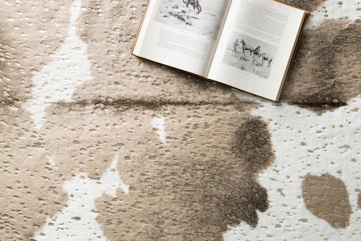 Close-up of taupe and champagne cowhide-style rug with abstract blotches and speckles