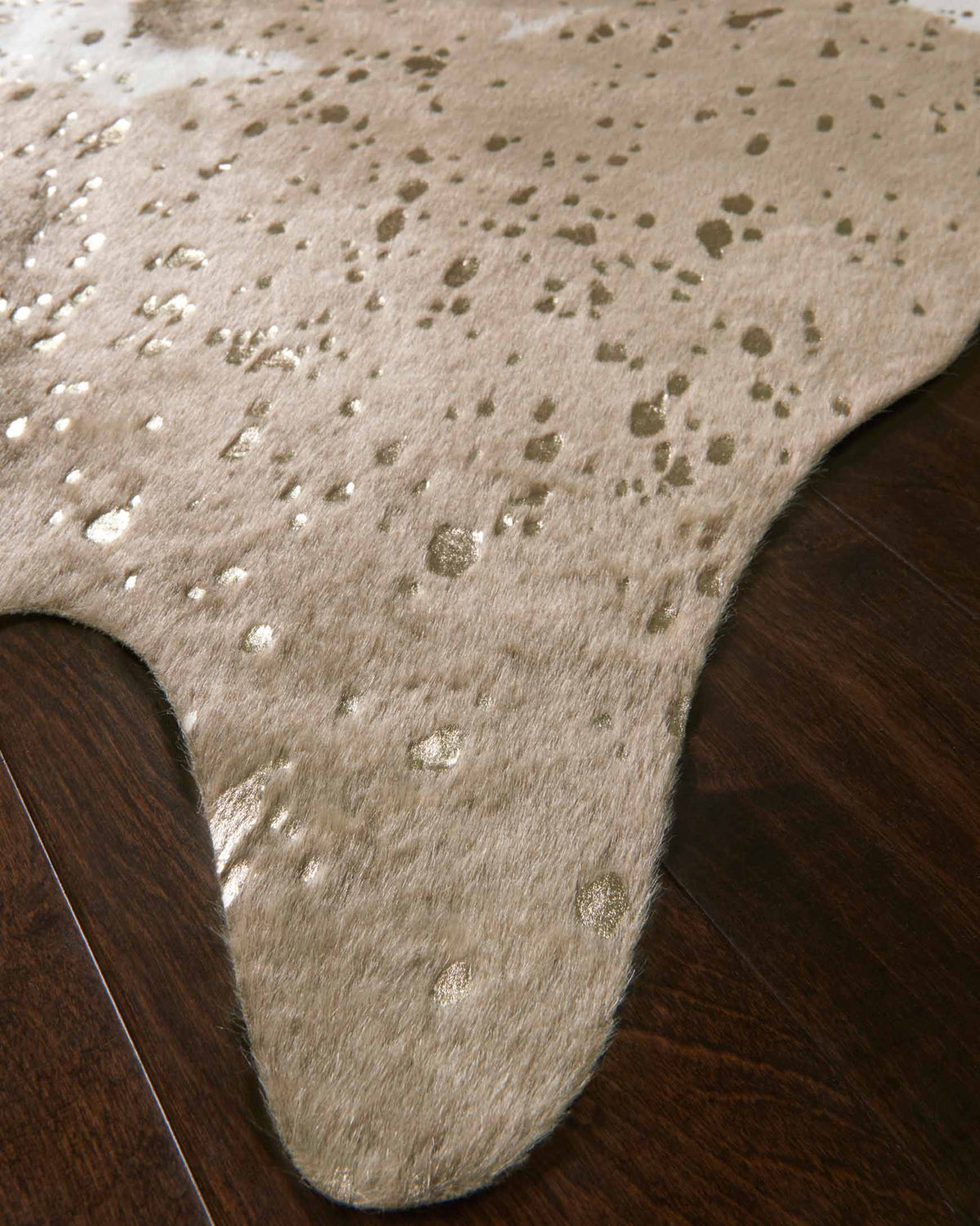 Taupe and champagne cowhide-style rug with scattered white speckles, short pile detail