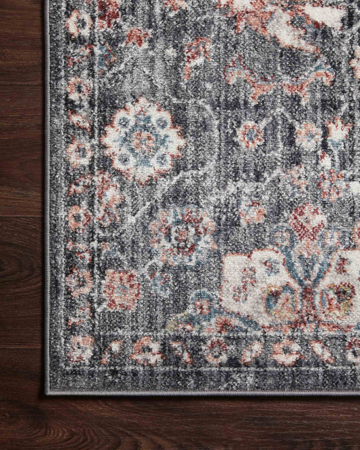 Close-up of charcoal rug surface showing distressed medallion motifs in rust and light blue