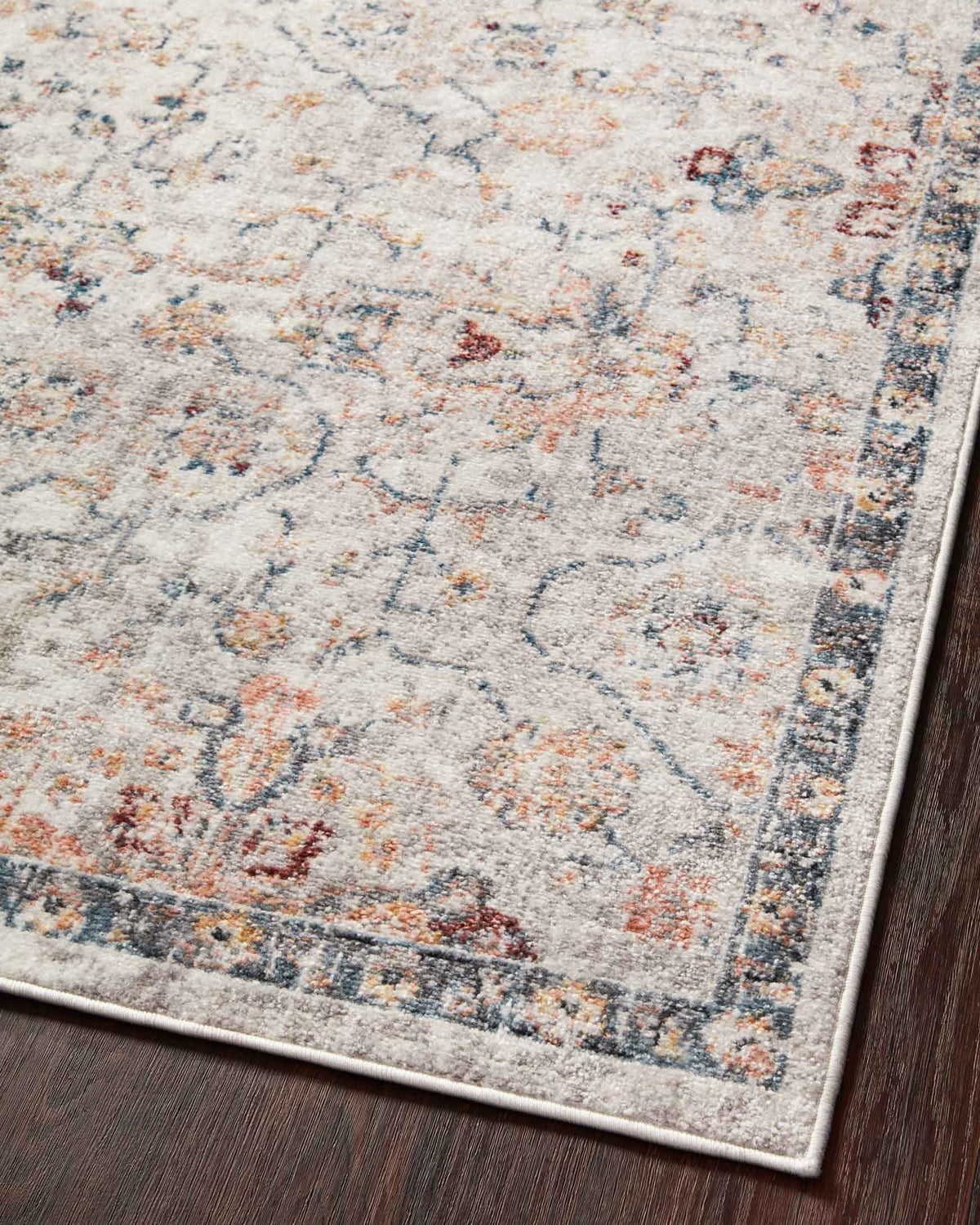Close-up of light dove rug with navy ornamental lines, speckled highlights, and border edge