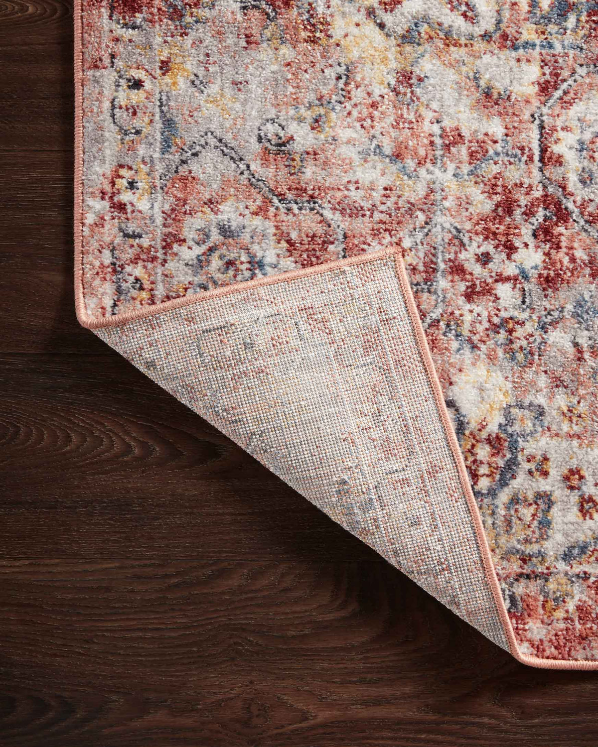 Rug corner close-up with stitched underside panel in ivory and border trim in rust.