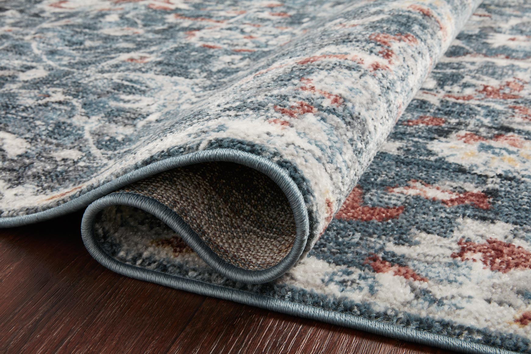 Blue and rust textured rug with stitched border, rolled edge detail