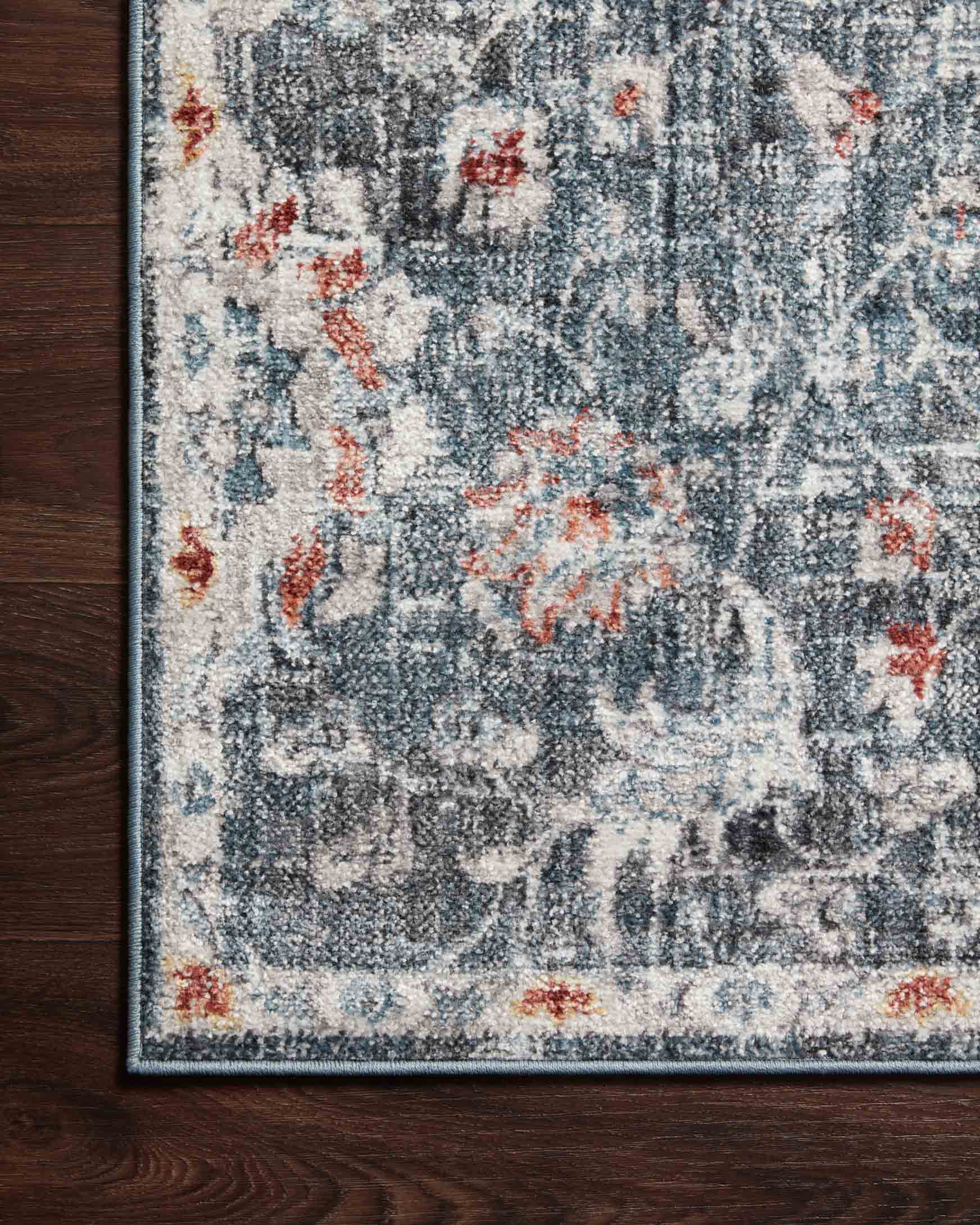 Corner of blue rug with rust accents and abstract medallion design