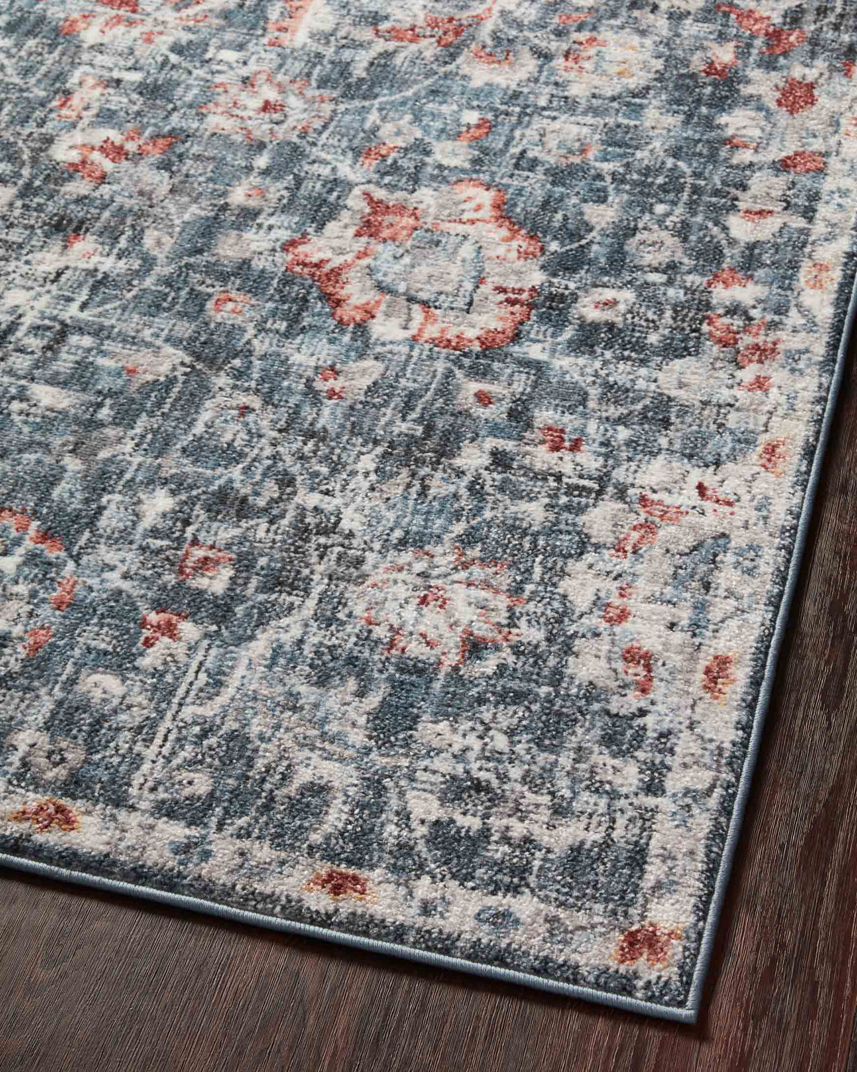 Blue area rug with rust and cream motifs in distressed abstract grid