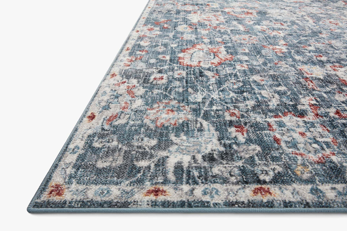 Blue rug corner with rust floral motifs and dark-trimmed edge