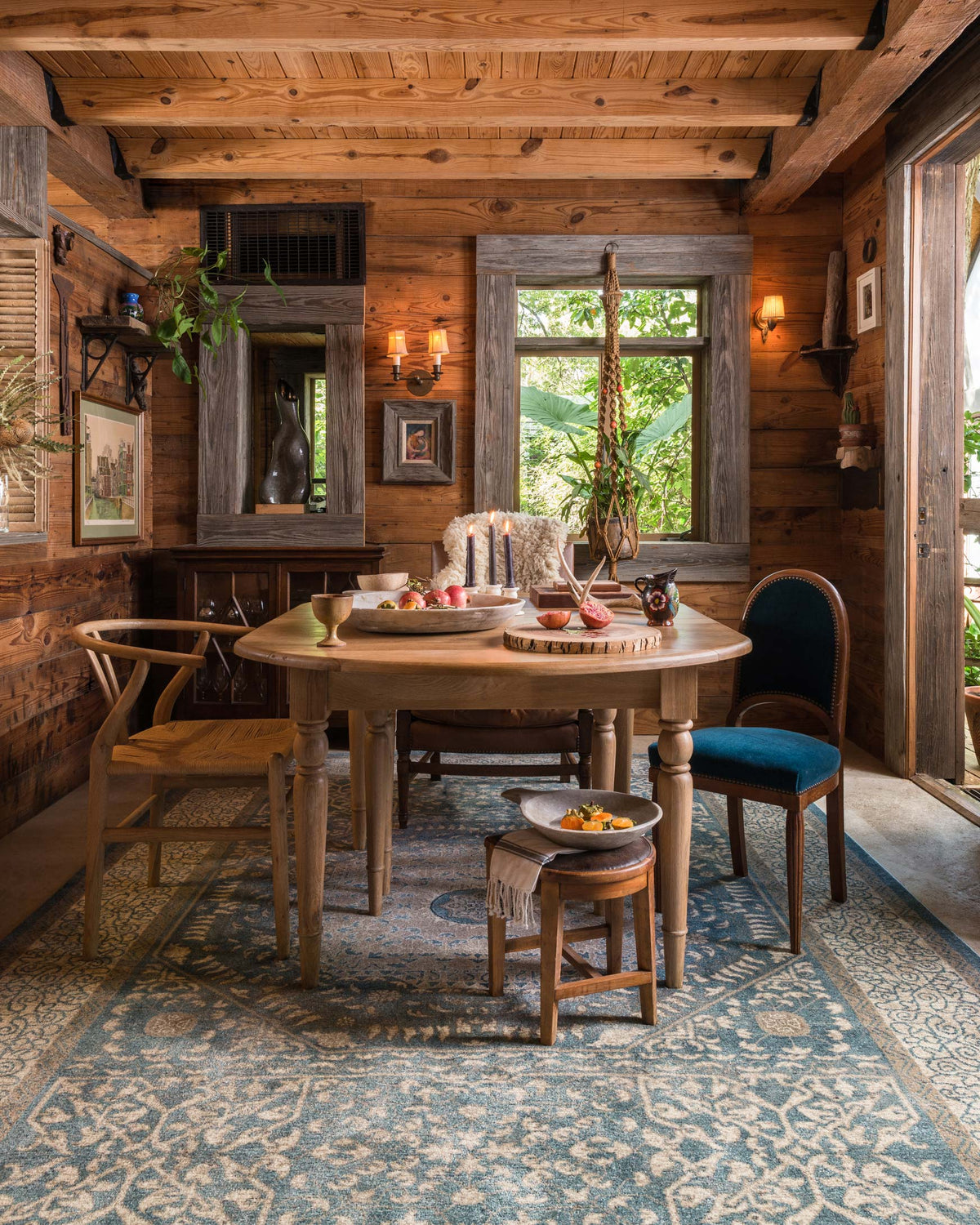 Blue and sand patterned rug with intricate ornamental motifs beneath dining seating.