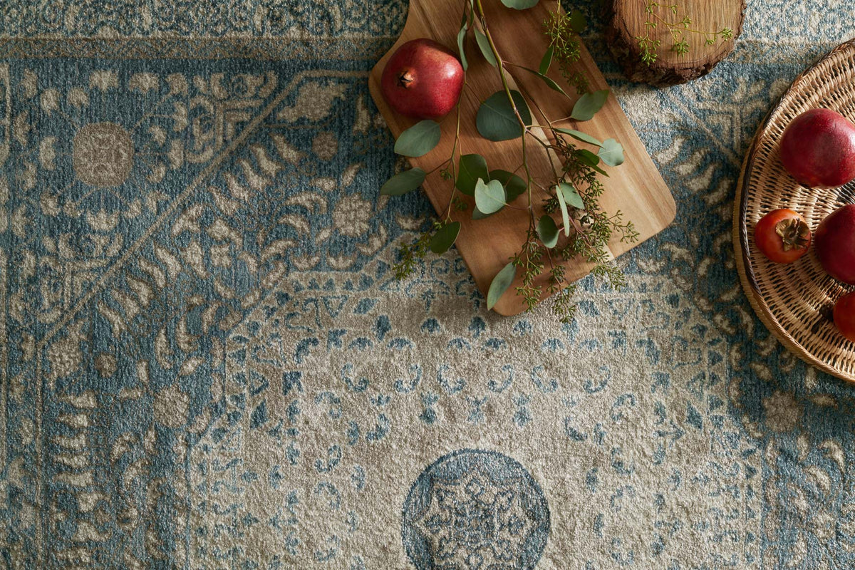 Blue and sand rug surface with decorative medallion and scrolling floral motifs.